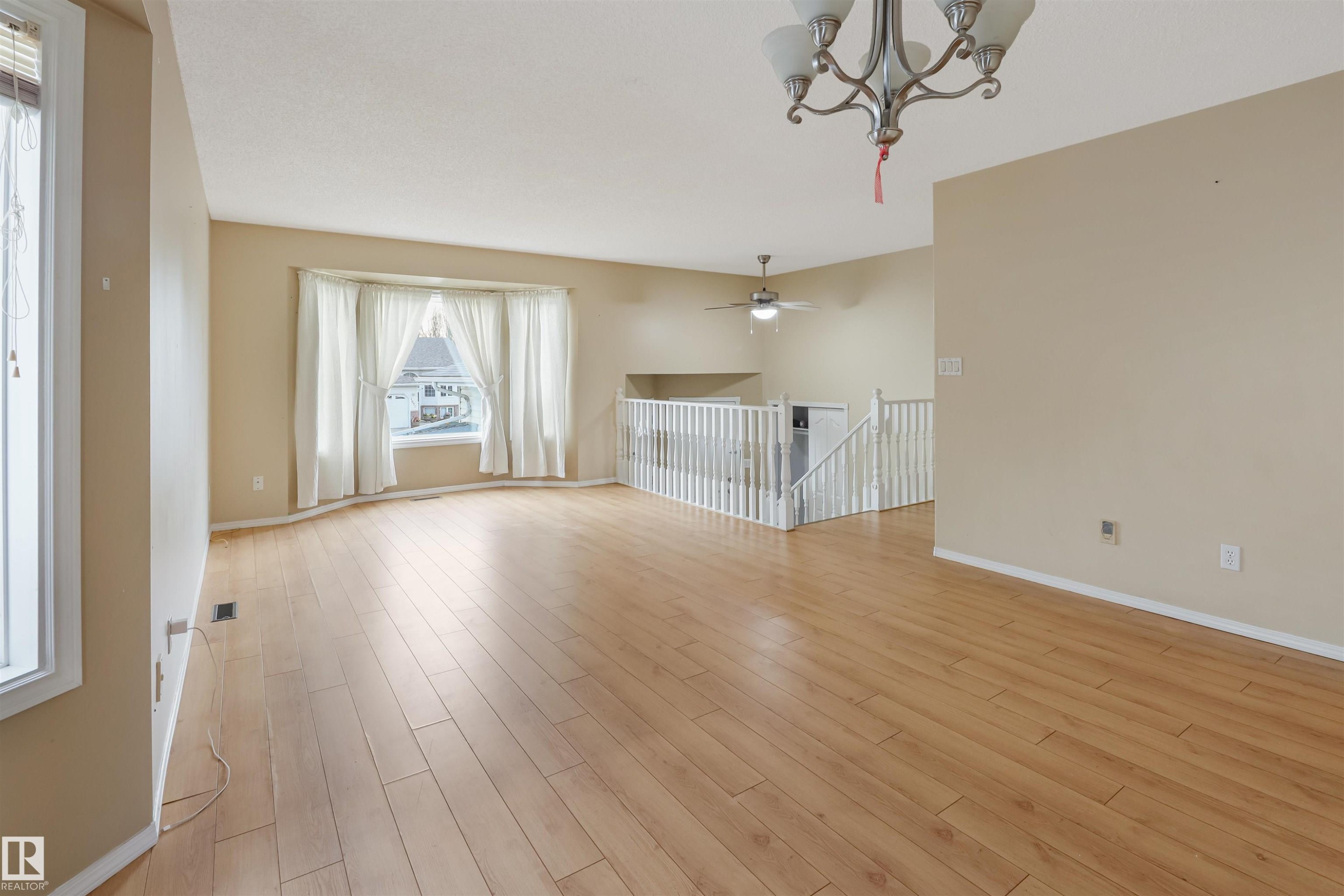 Spacious interior with wood-finish flooring, a bay window, and a chandelier - 1055 Jones Crescent Nw, Edmonton, AB - Indoor