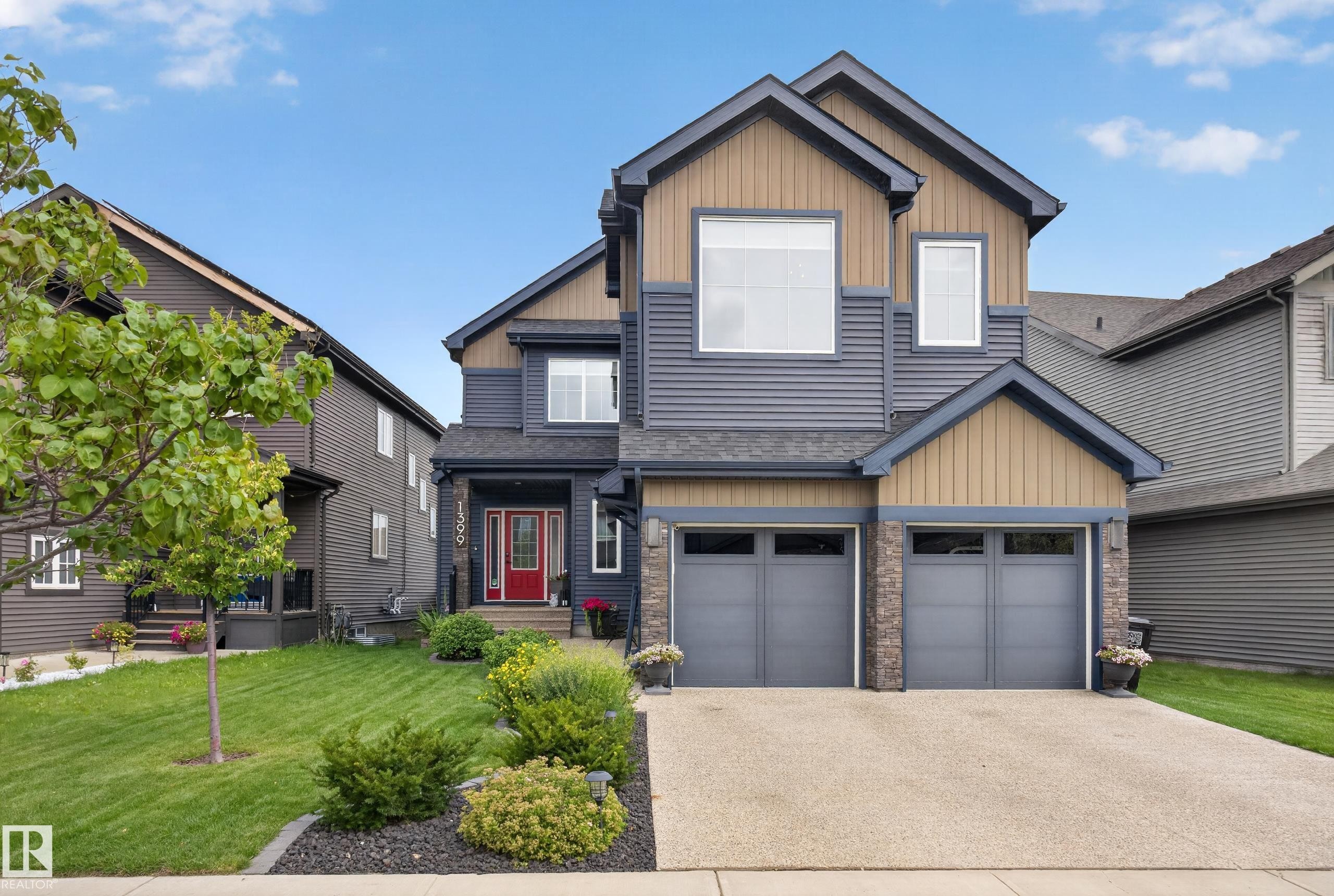Multi-level exterior with mixed siding, stone accents, and a red entry door - 1399 Graydon Hill Way Sw, Edmonton, AB