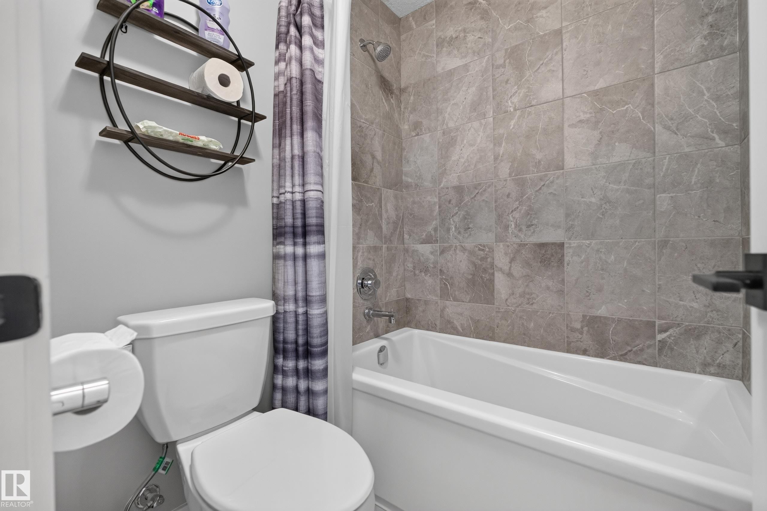 Bathtub with tiled surround, chrome shower fixtures, and white toilet - 1399 Graydon Hill Way Sw, Edmonton, AB