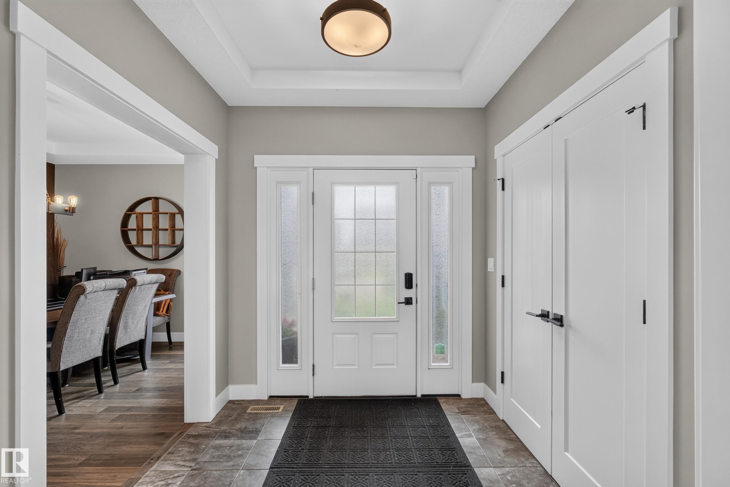 Entryway featuring a white paneled door with sidelights, tray ceiling, and tile flooring - 1399 Graydon Hill Way Sw, Edmonton, AB