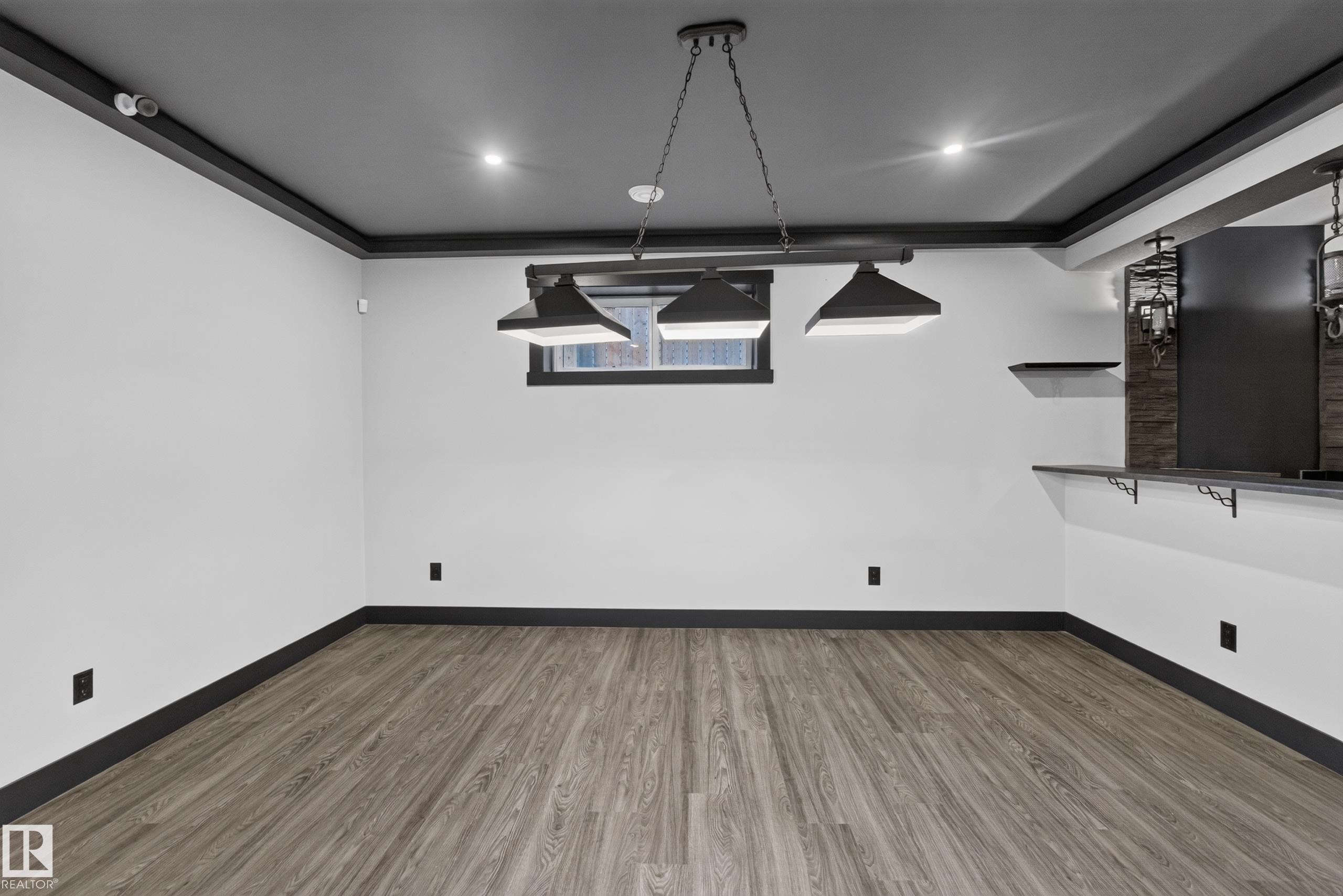 Wood-finish flooring, recessed lighting, industrial-style pendant lighting, built-in shelf, and a built-in counter - 1399 Graydon Hill Way Sw, Edmonton, AB
