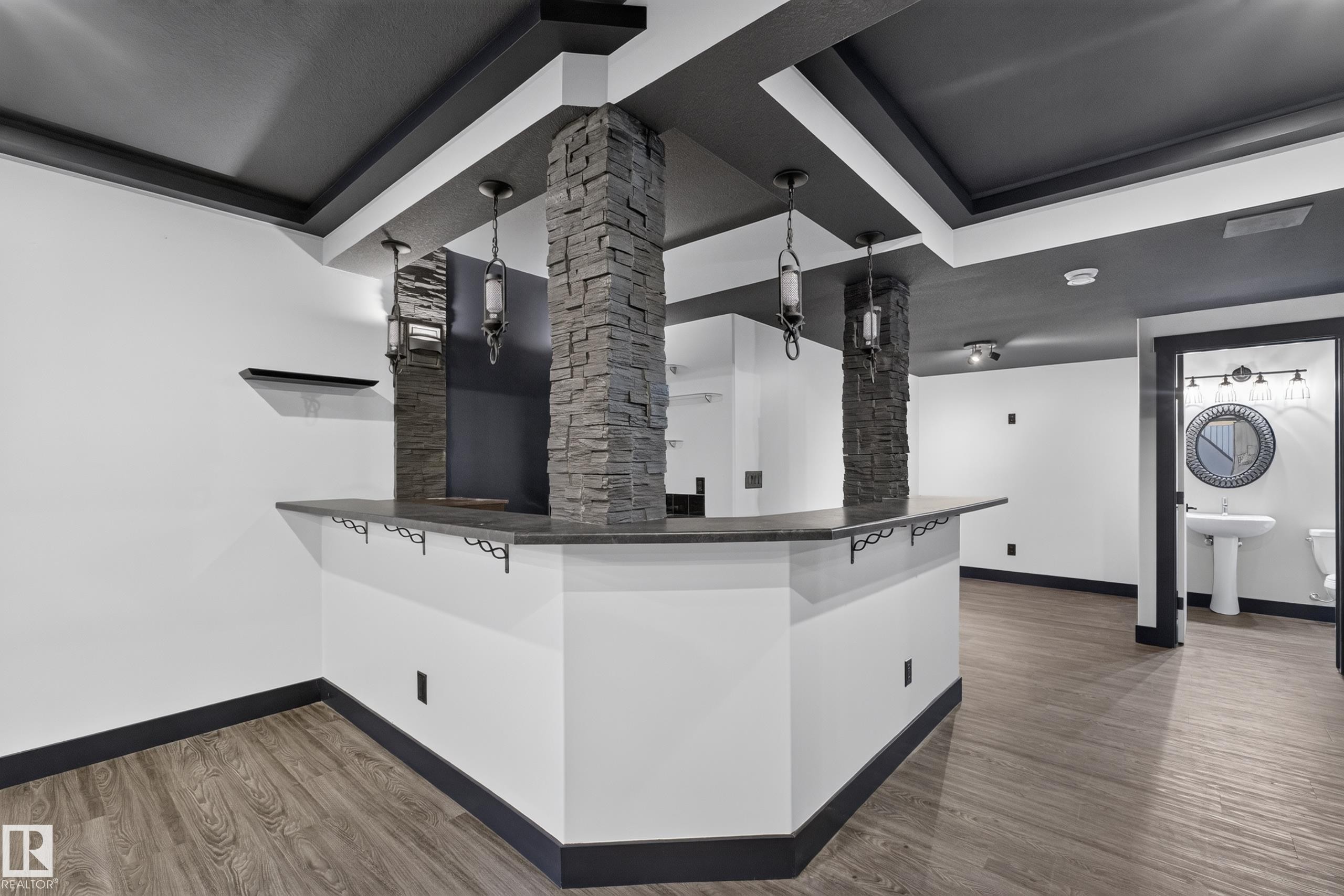 Built-in bar with a stone-clad support pillar, pendant lighting, and a dark countertop - 1399 Graydon Hill Way Sw, Edmonton, AB