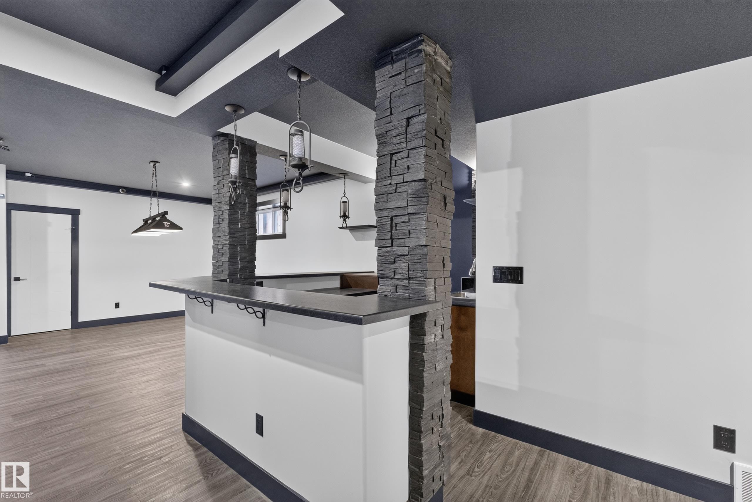 Built-in bar with stone-clad pillars, pendant lighting, and wood-finish flooring - 1399 Graydon Hill Way Sw, Edmonton, AB