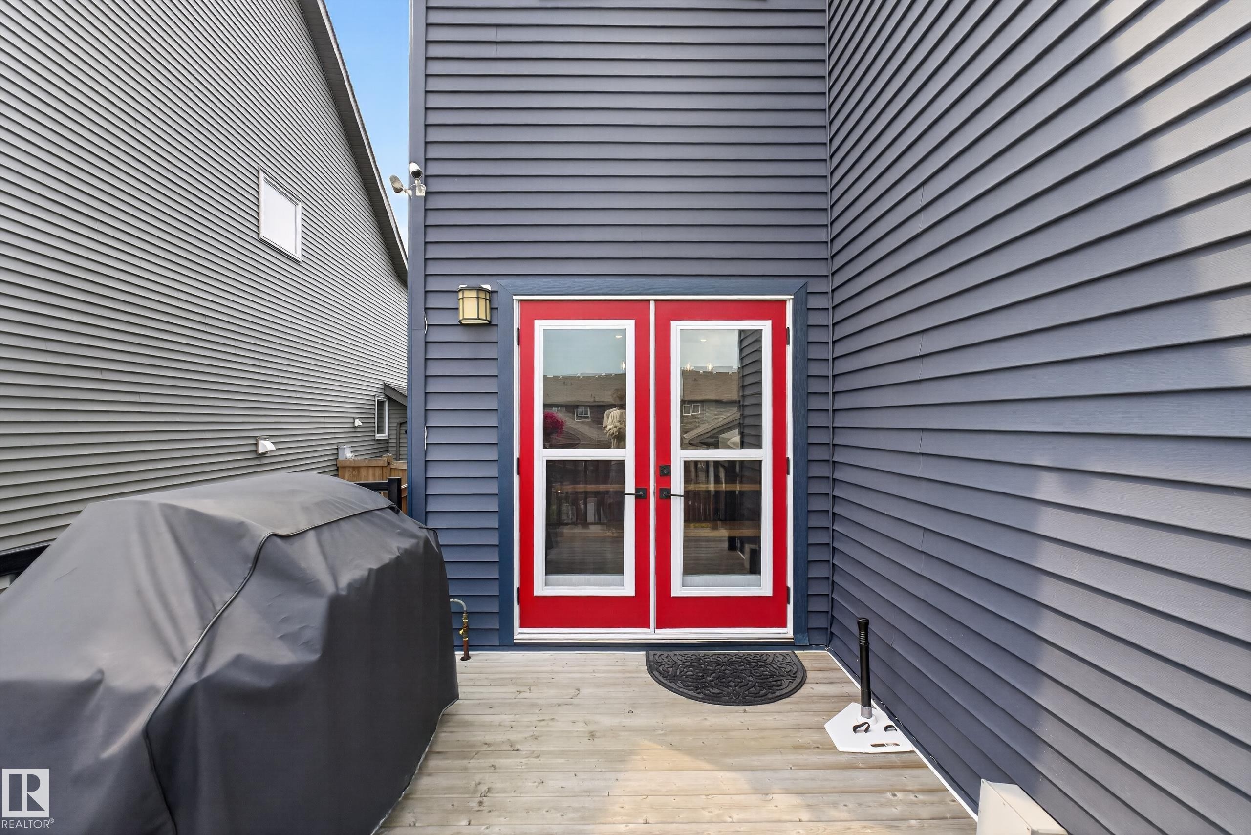 Gray siding exterior featuring red framed glass panel doors and a wood-finish deck - 1399 Graydon Hill Way Sw, Edmonton, AB