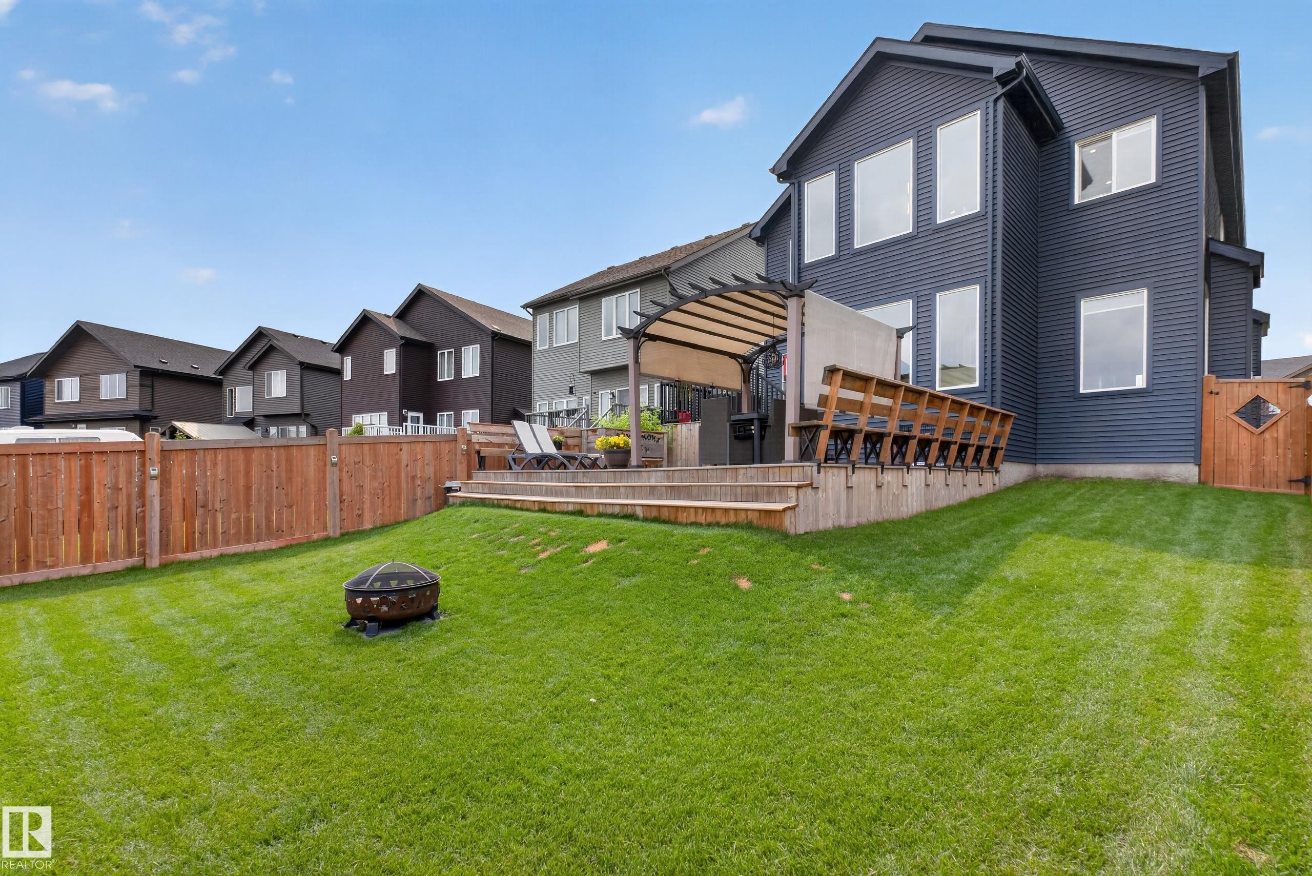 Expansive backyard featuring a tiered wood deck with pergola, wood fence, and a generous lawn - 1399 Graydon Hill Way Sw, Edmonton, AB