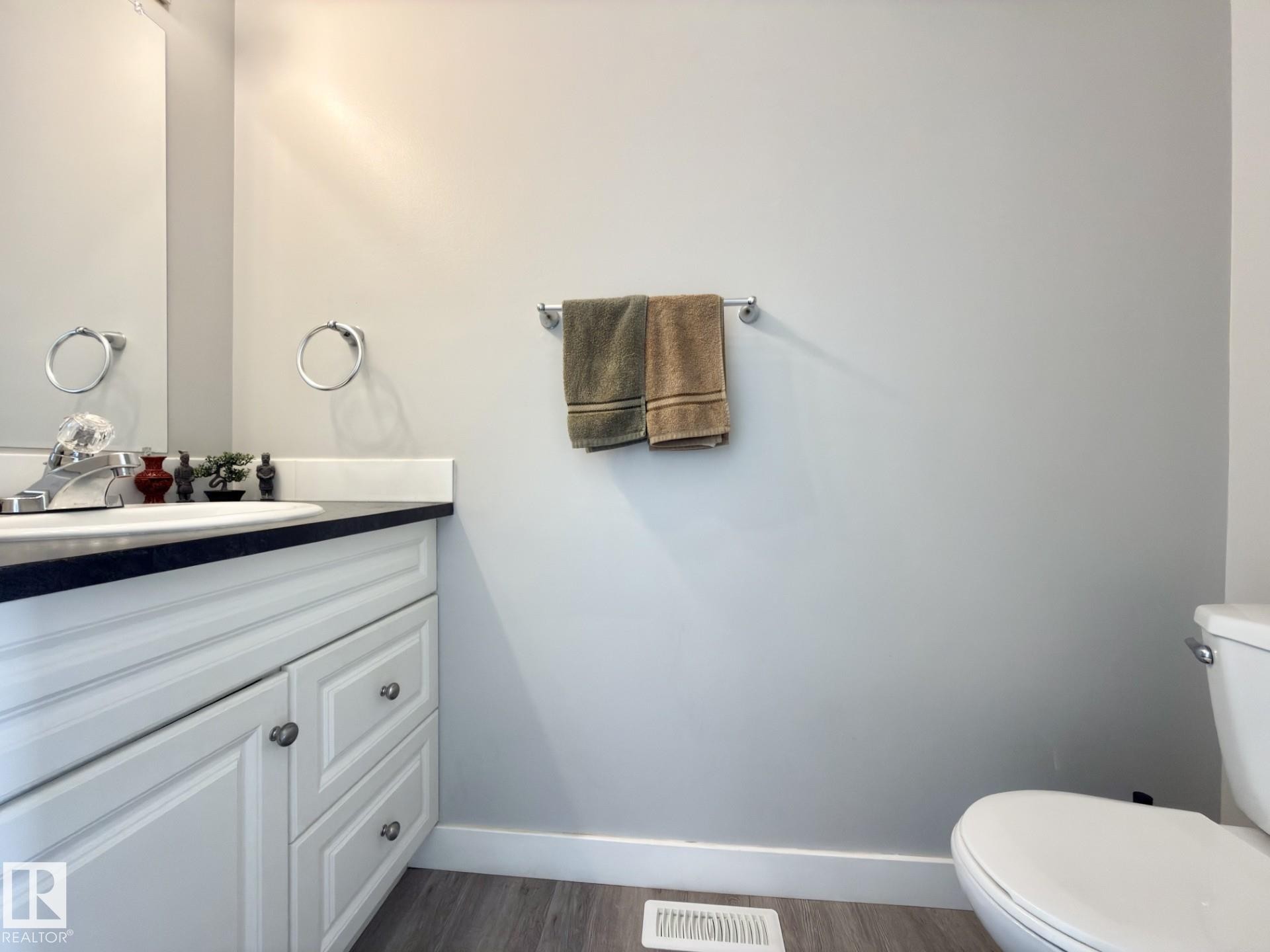 White vanity with paneled doors and drawers, dark countertop, and integrated sink - #13 18010 98 Av Nw Nw, Edmonton, AB - Indoor Photo Showing Bathroom