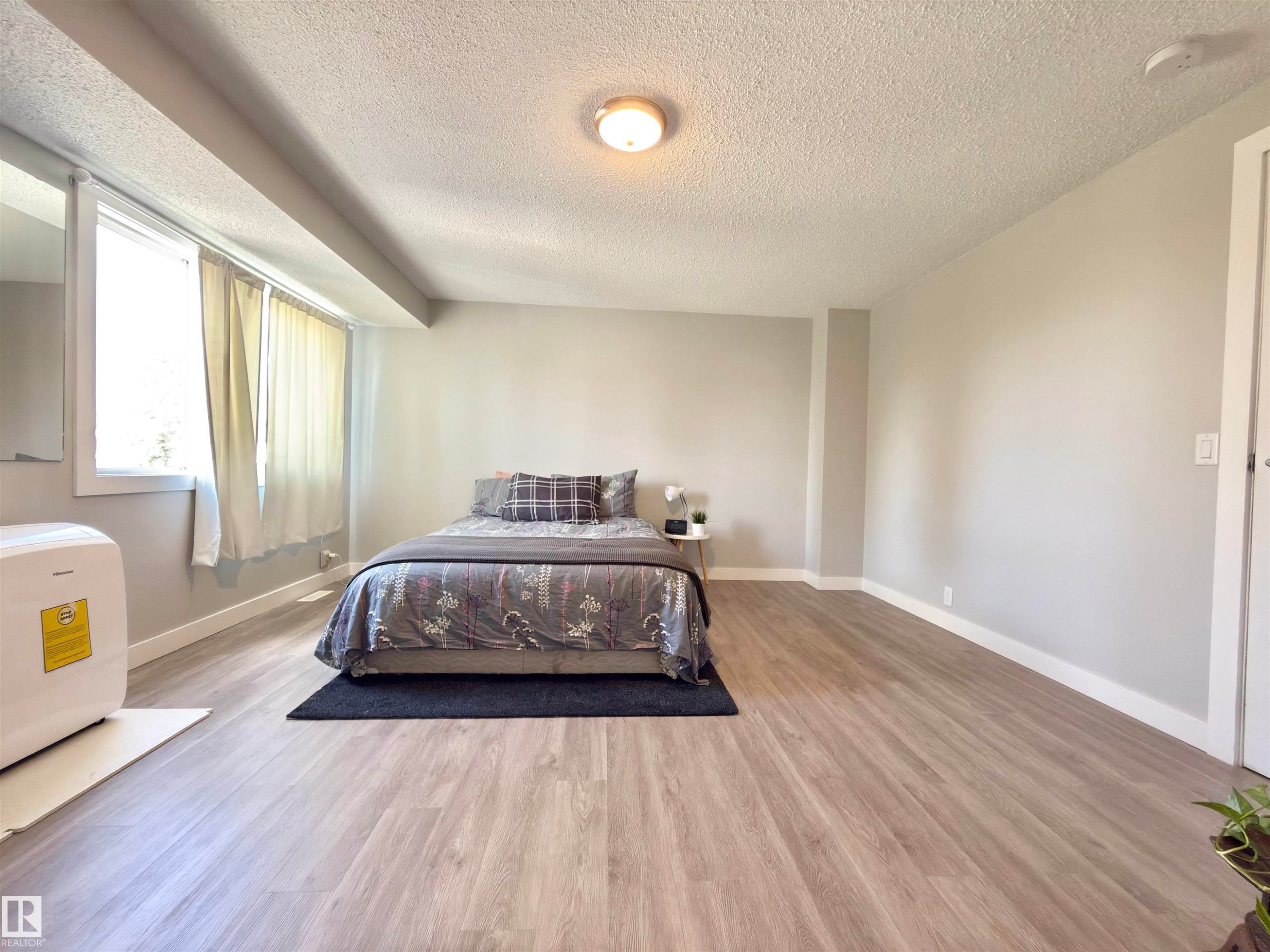 Recessed window, wood-finish flooring, light gray wall color, white trim, and a ceiling-mounted light fixture - #13 18010 98 Av Nw Nw, Edmonton, AB - Indoor Photo Showing Bedroom