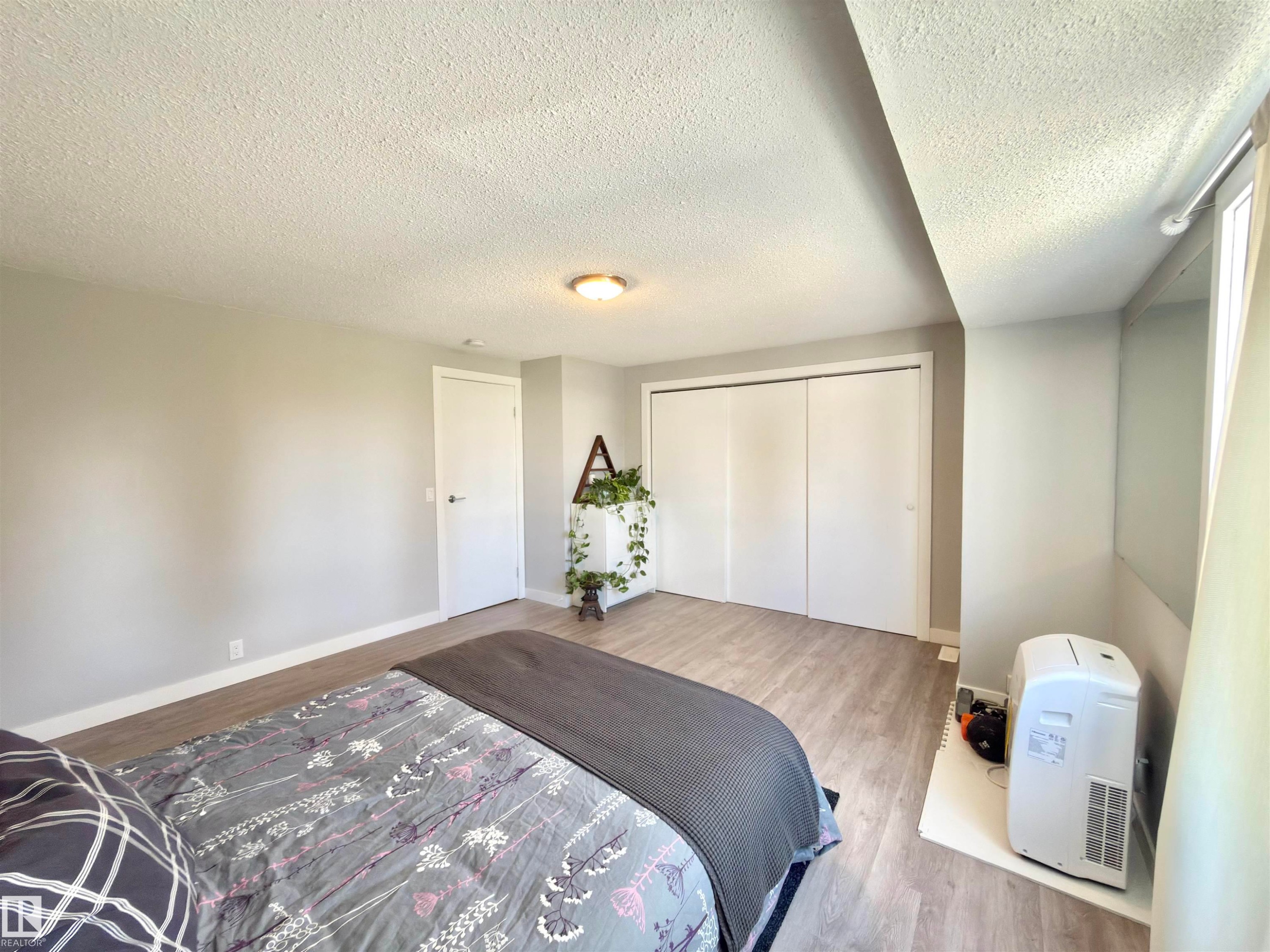 Light-hued wood-finish flooring, white walls, and a ceiling-mounted light fixture - #13 18010 98 Av Nw Nw, Edmonton, AB - Indoor Photo Showing Bedroom