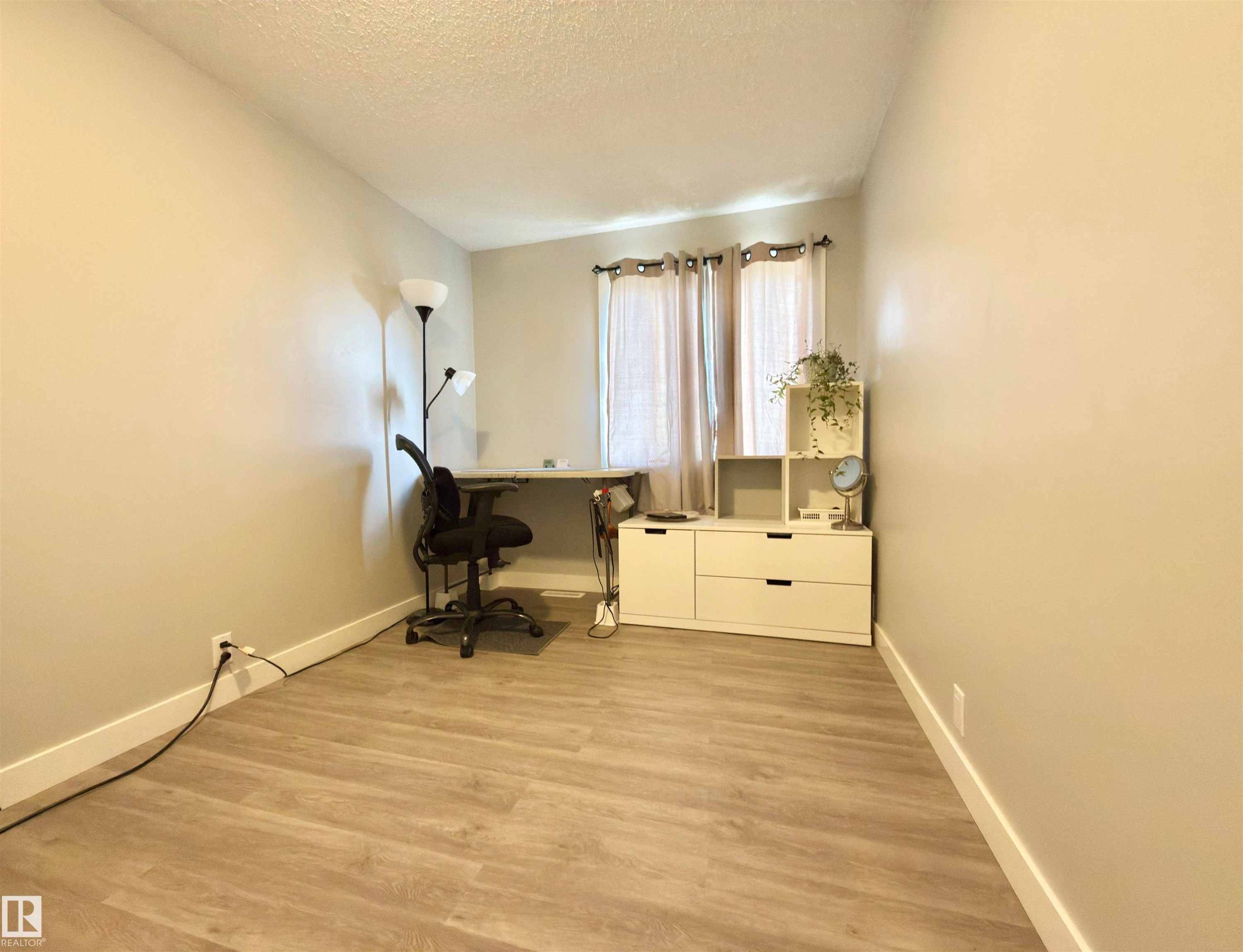 Wood-finish flooring, neutral wall paint, and window with natural light - #13 18010 98 Av Nw Nw, Edmonton, AB - Indoor