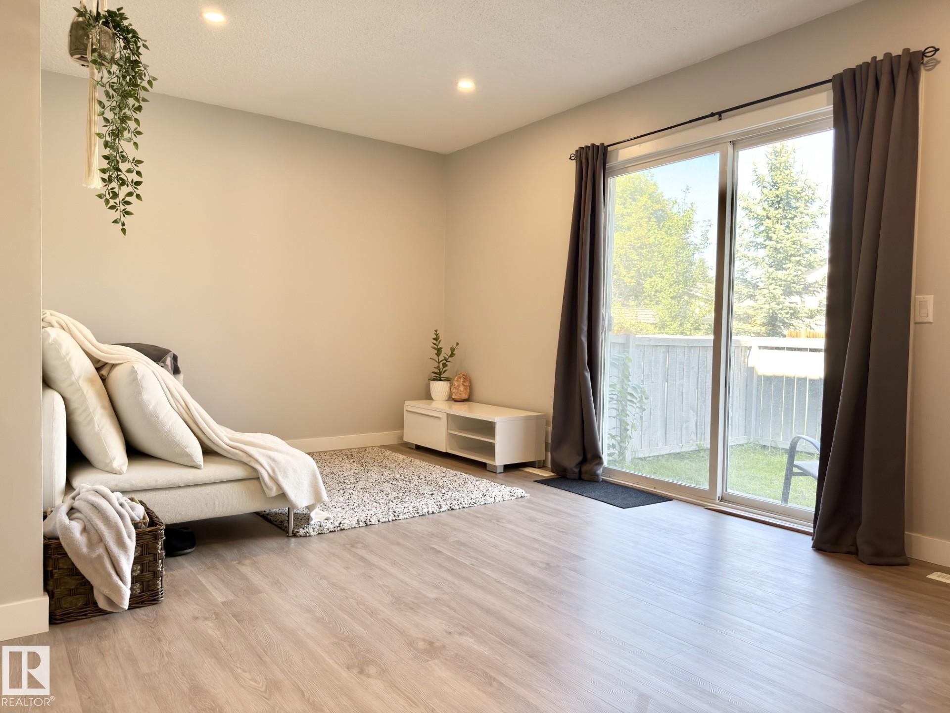 Wood-finish flooring, recessed ceiling lighting, and a sliding glass door - #13 18010 98 Av Nw Nw, Edmonton, AB - Indoor