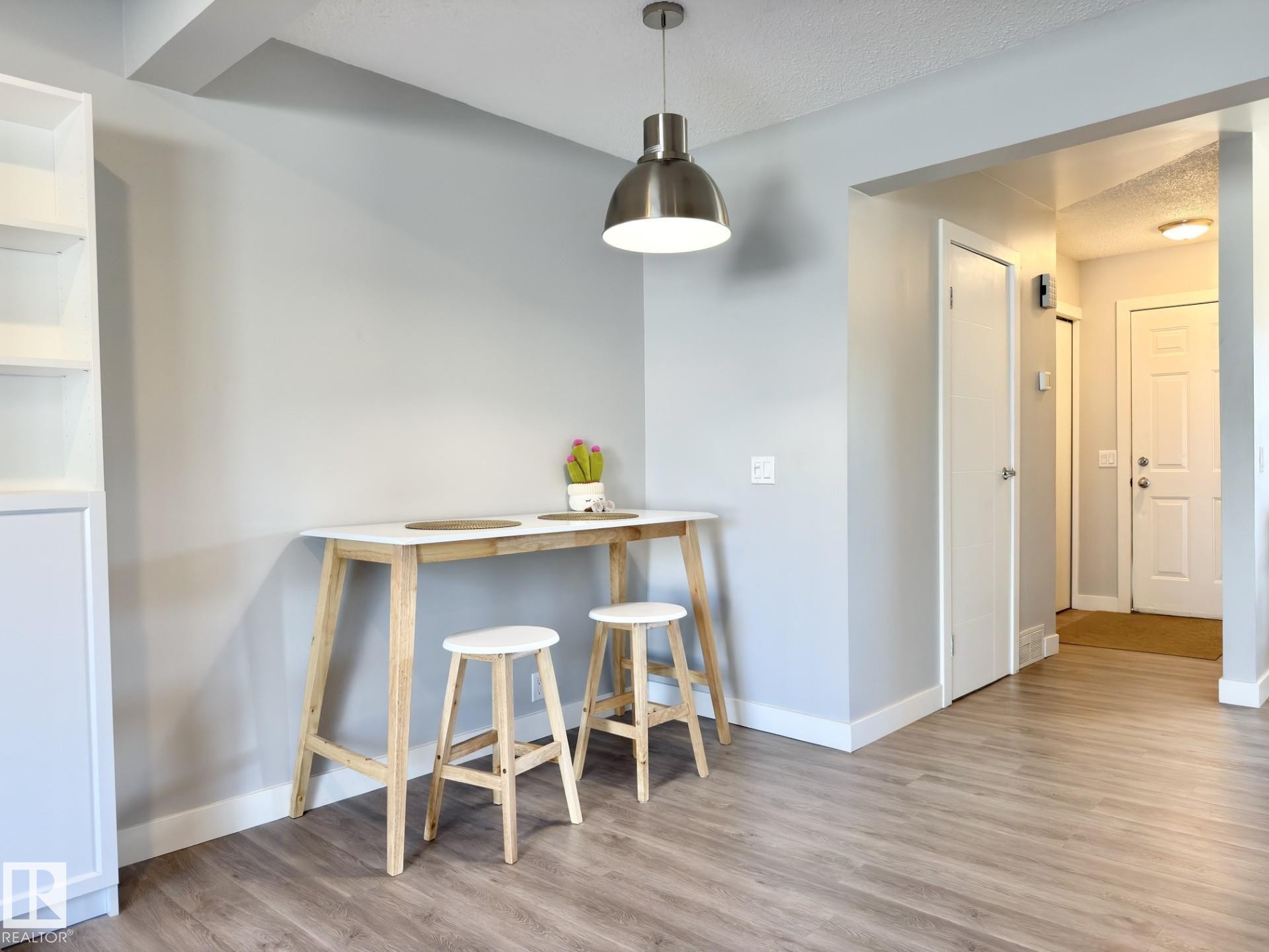 Wood-finish flooring throughout, modern pendant lighting, built-in shelving, and white interior doors - #13 18010 98 Av Nw Nw, Edmonton, AB - Indoor