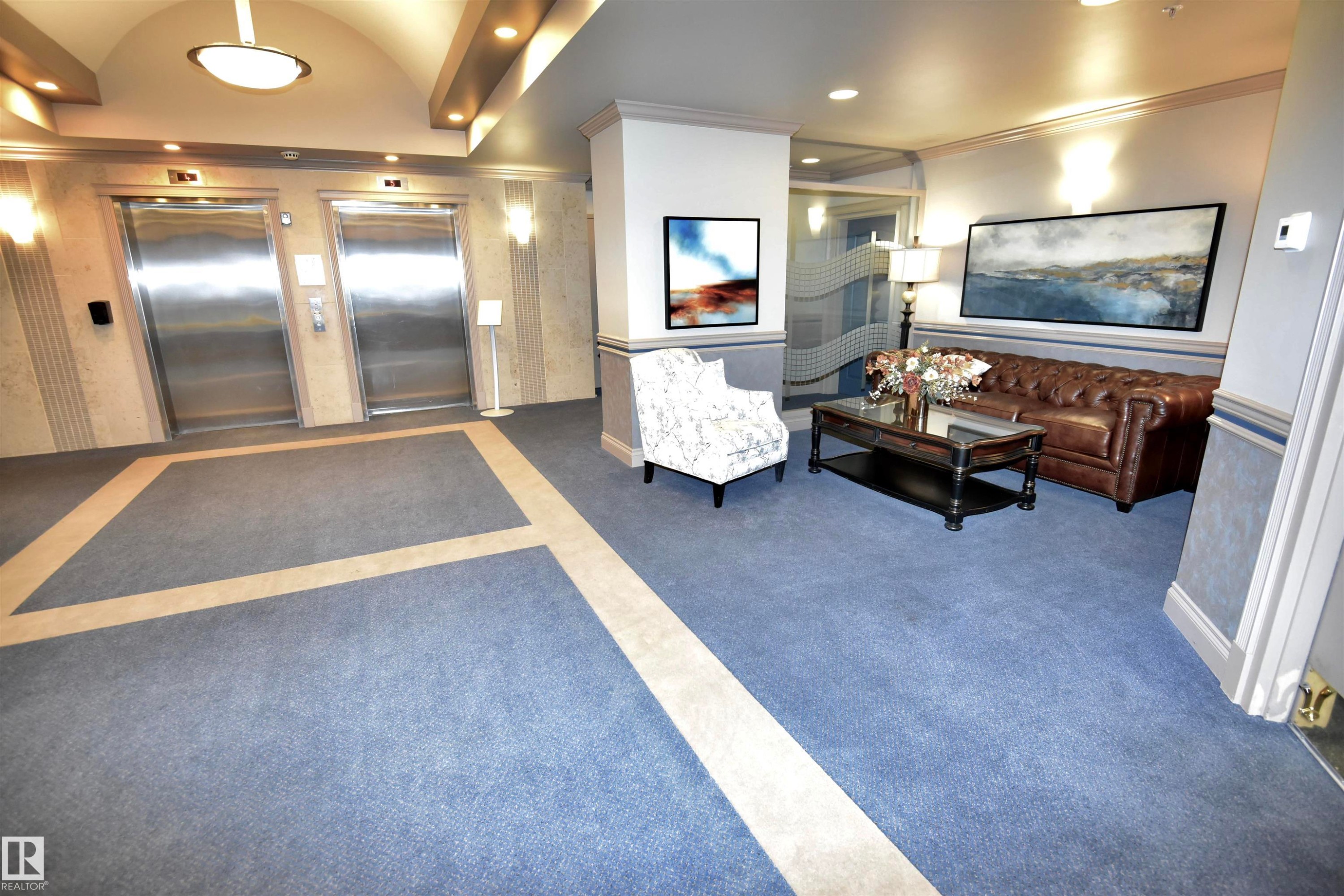 Lobby area featuring two stainless steel elevators, patterned blue carpeting with a light-colored inlay, and recessed lighting - #706 9741 110 St Nw, Edmonton, AB - Indoor Photo Showing Other Room