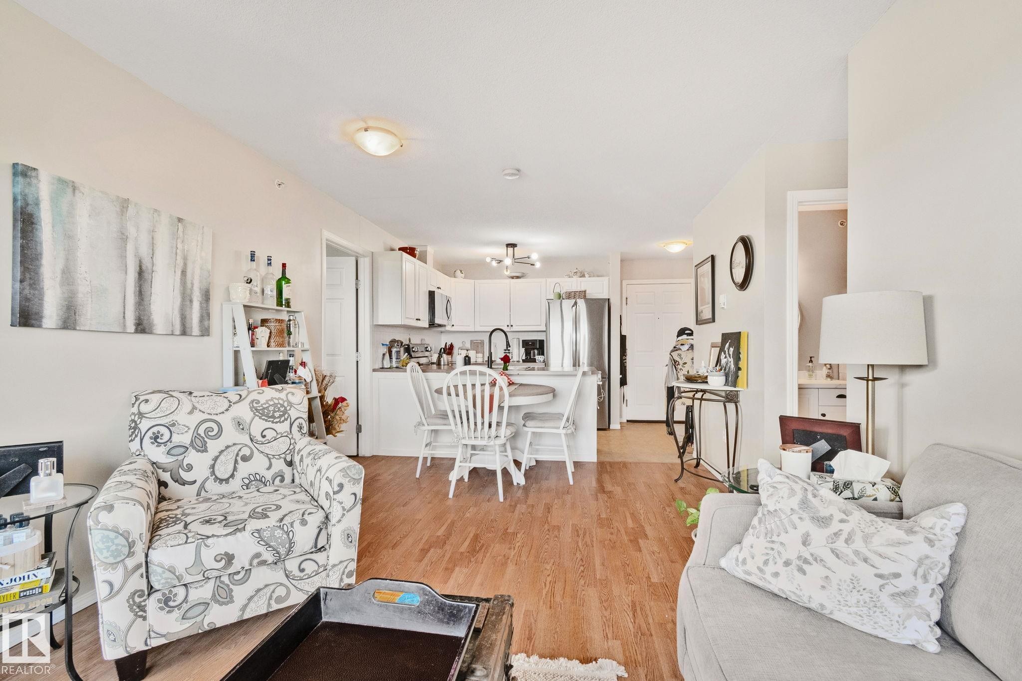 Open-concept living space featuring wood-finish flooring, recessed lighting, and a kitchen with white cabinetry - #407 4309 33 St, Stony Plain, AB - Indoor Photo Showing Living Room