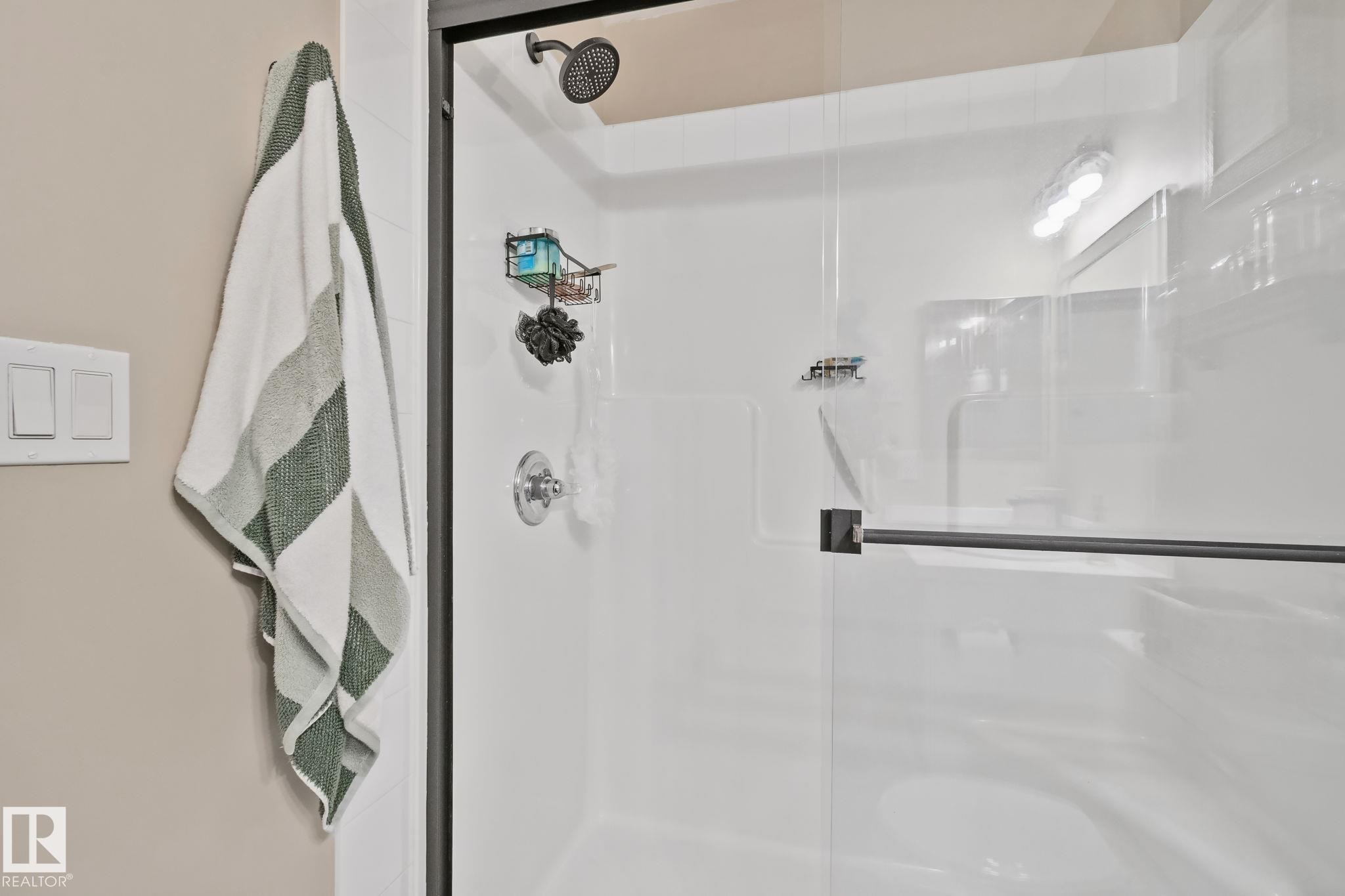 Glass-enclosed shower with a matte black frame, rain showerhead, and polished chrome fixtures - #407 4309 33 St, Stony Plain, AB - Indoor Photo Showing Bathroom