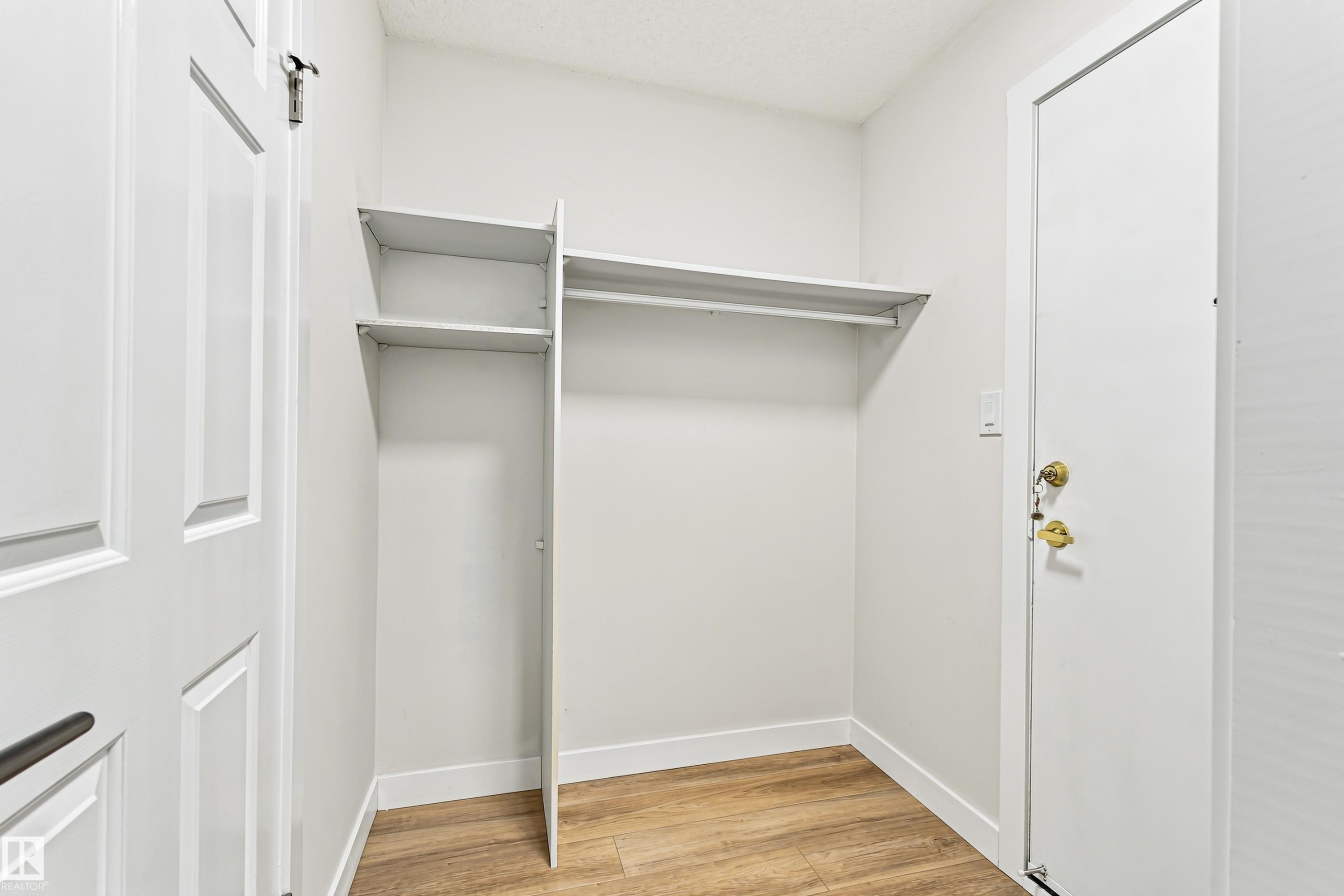 Wood-finish flooring, built-in shelving, and white paneled doors - #21 9375 172 St Nw, Edmonton, AB - Indoor With Storage