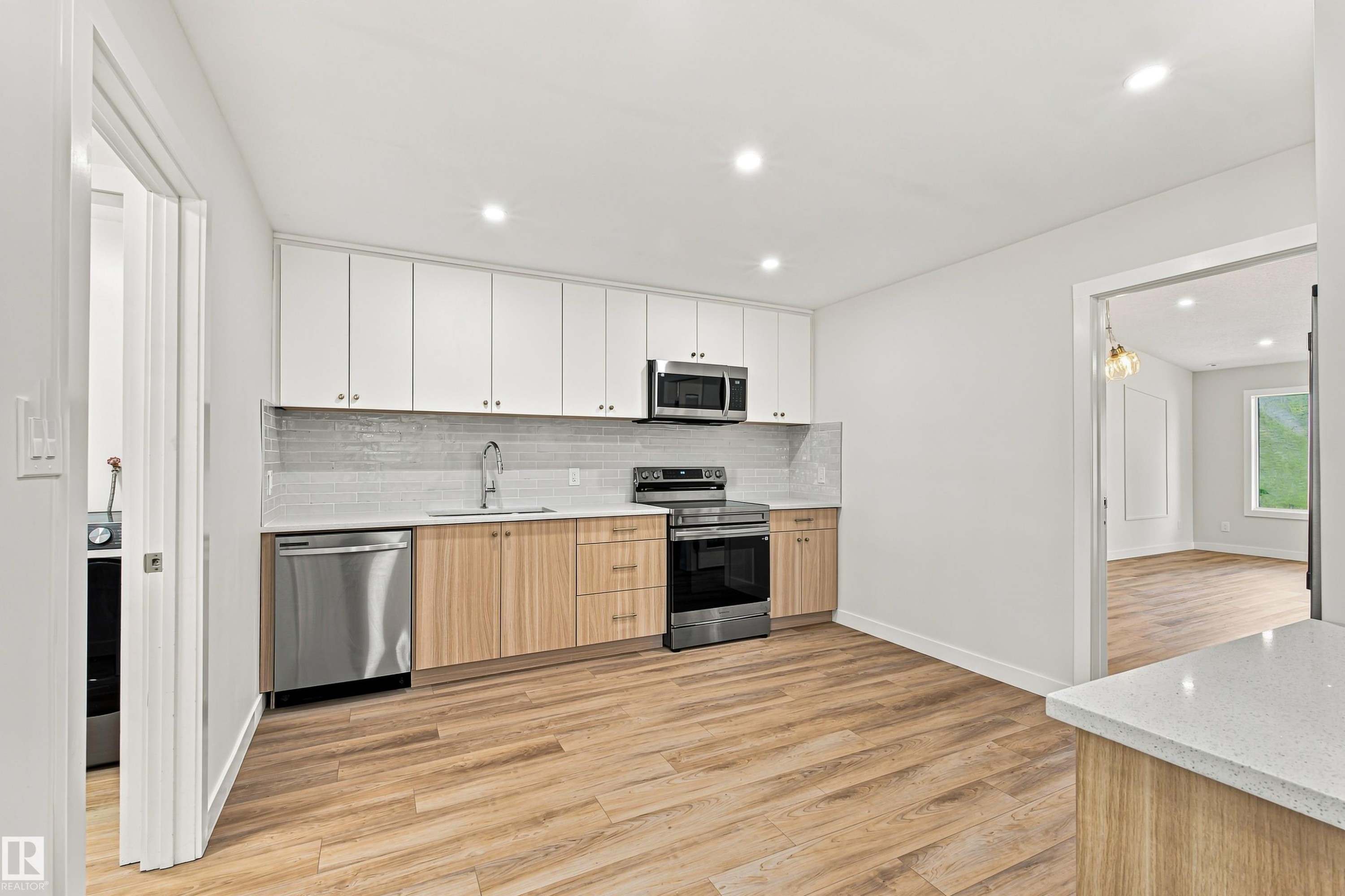 Kitchen featuring wood-finish flooring, two-tone cabinetry, stainless steel appliances, a tile backsplash, and recessed lighting - #21 9375 172 St Nw, Edmonton, AB - Indoor Photo Showing Kitchen With Upgraded Kitchen