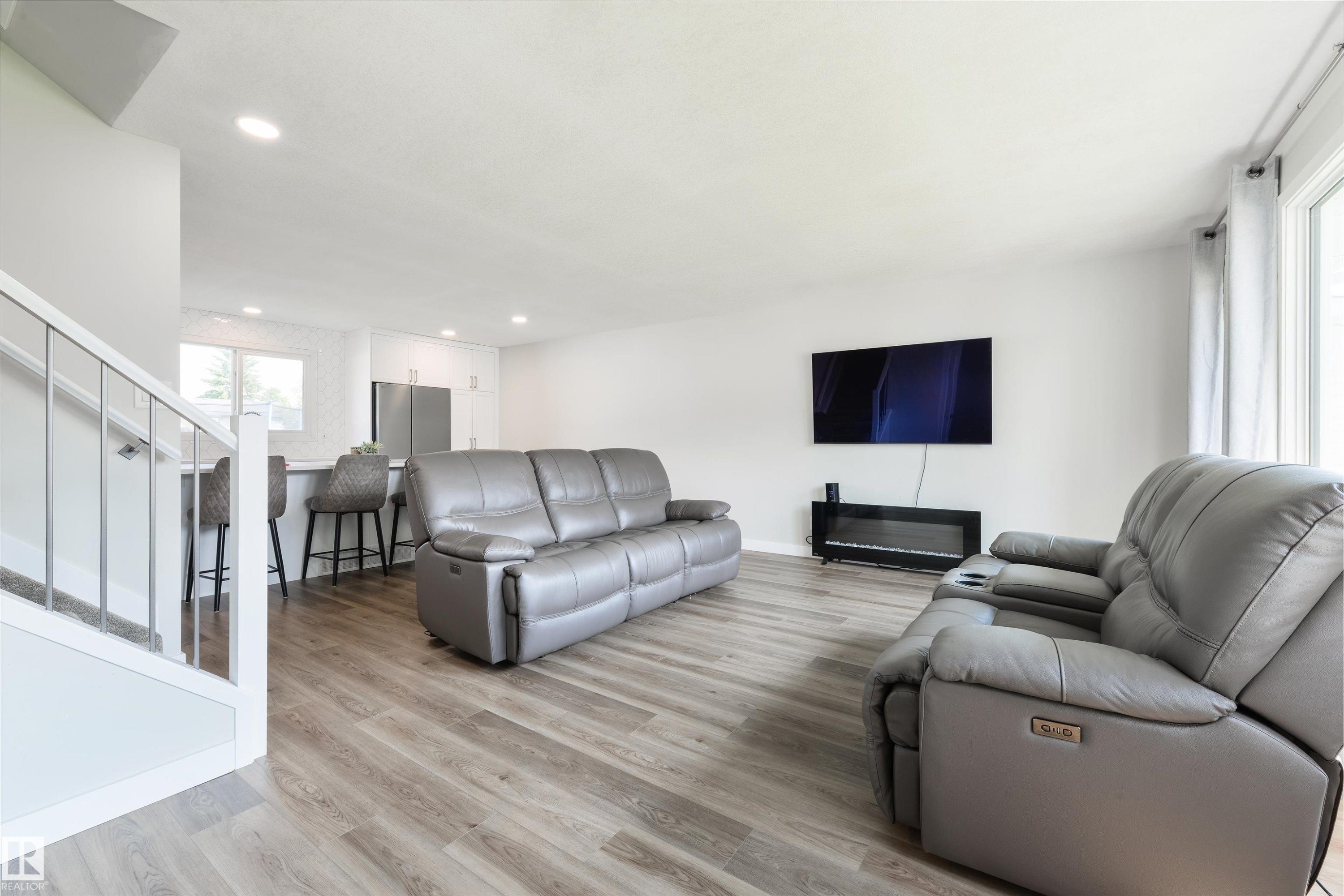 Bright open-concept living space featuring wood-finish flooring, recessed lighting, and a modern electric fireplace - 4614 53 Ave, Calmar, AB - Indoor Photo Showing Living Room