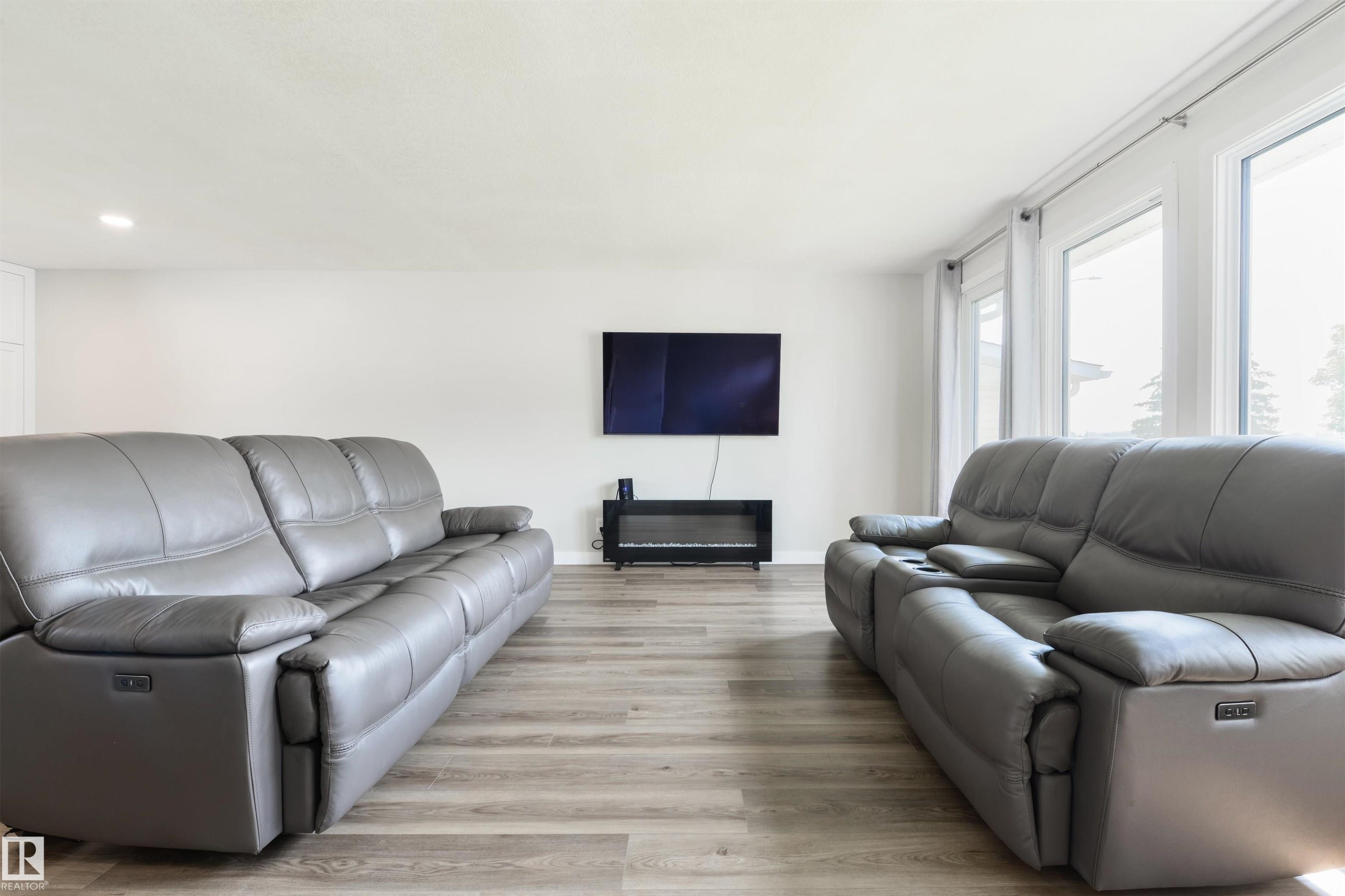 White walls, wood-finish flooring, recessed ceiling lighting, and multiple large windows - 4614 53 Ave, Calmar, AB - Indoor Photo Showing Living Room With Fireplace