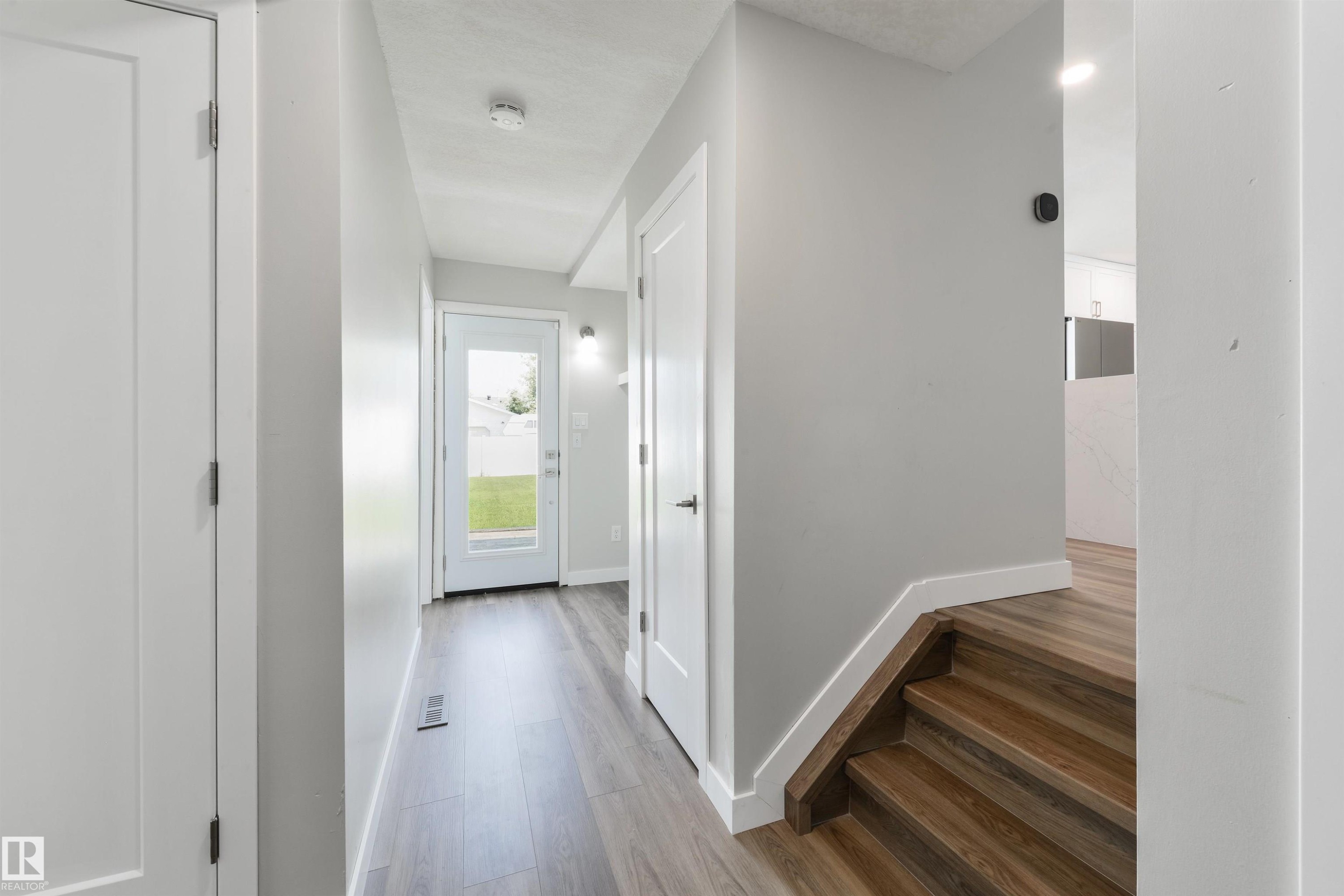 Wood-finish flooring throughout, white interior doors, and a full-light rear door - 4614 53 Ave, Calmar, AB - Indoor Photo Showing Other Room