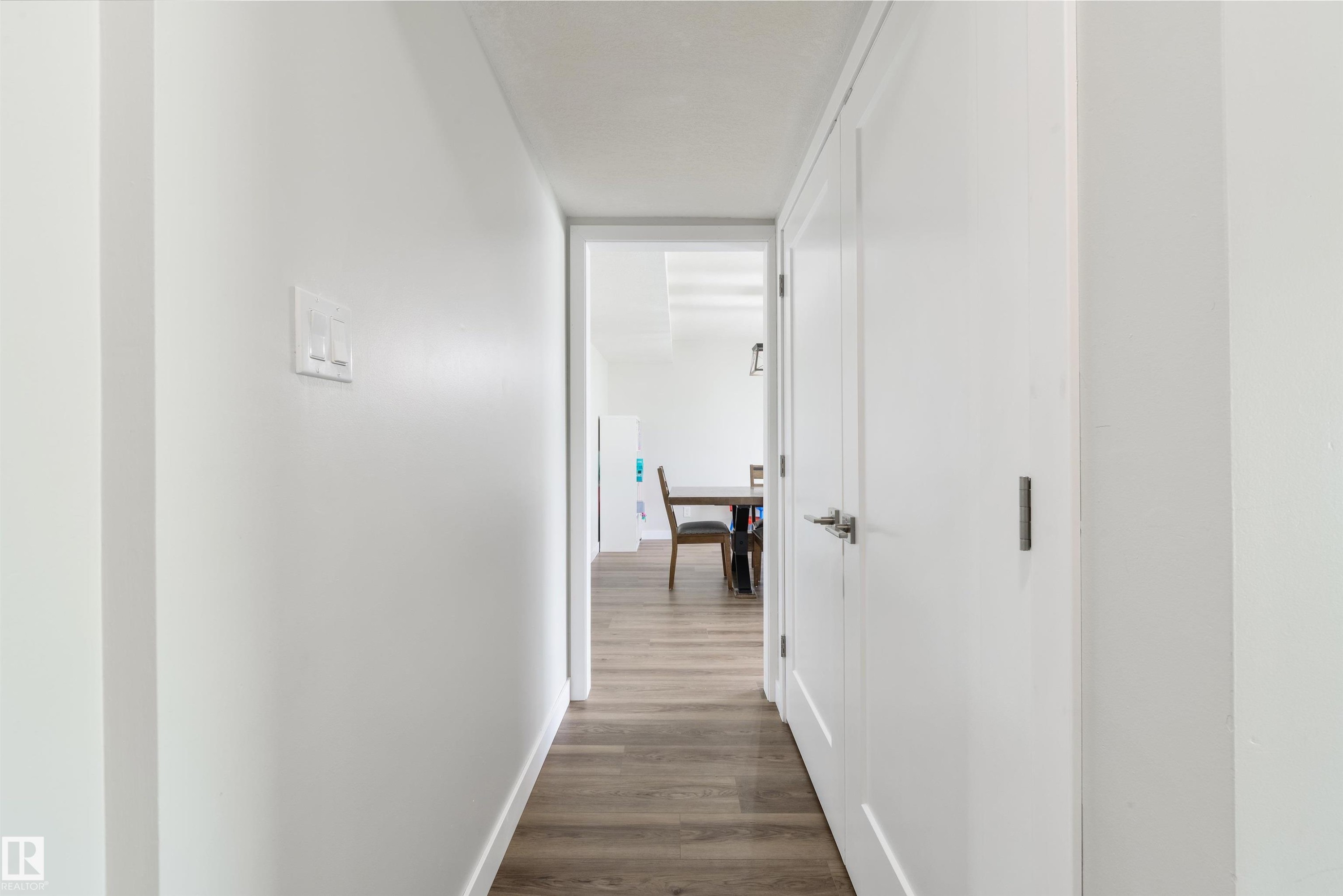 Hallway featuring wood-finish flooring, white walls, and white doors with contemporary hardware - 4614 53 Ave, Calmar, AB - Indoor Photo Showing Other Room