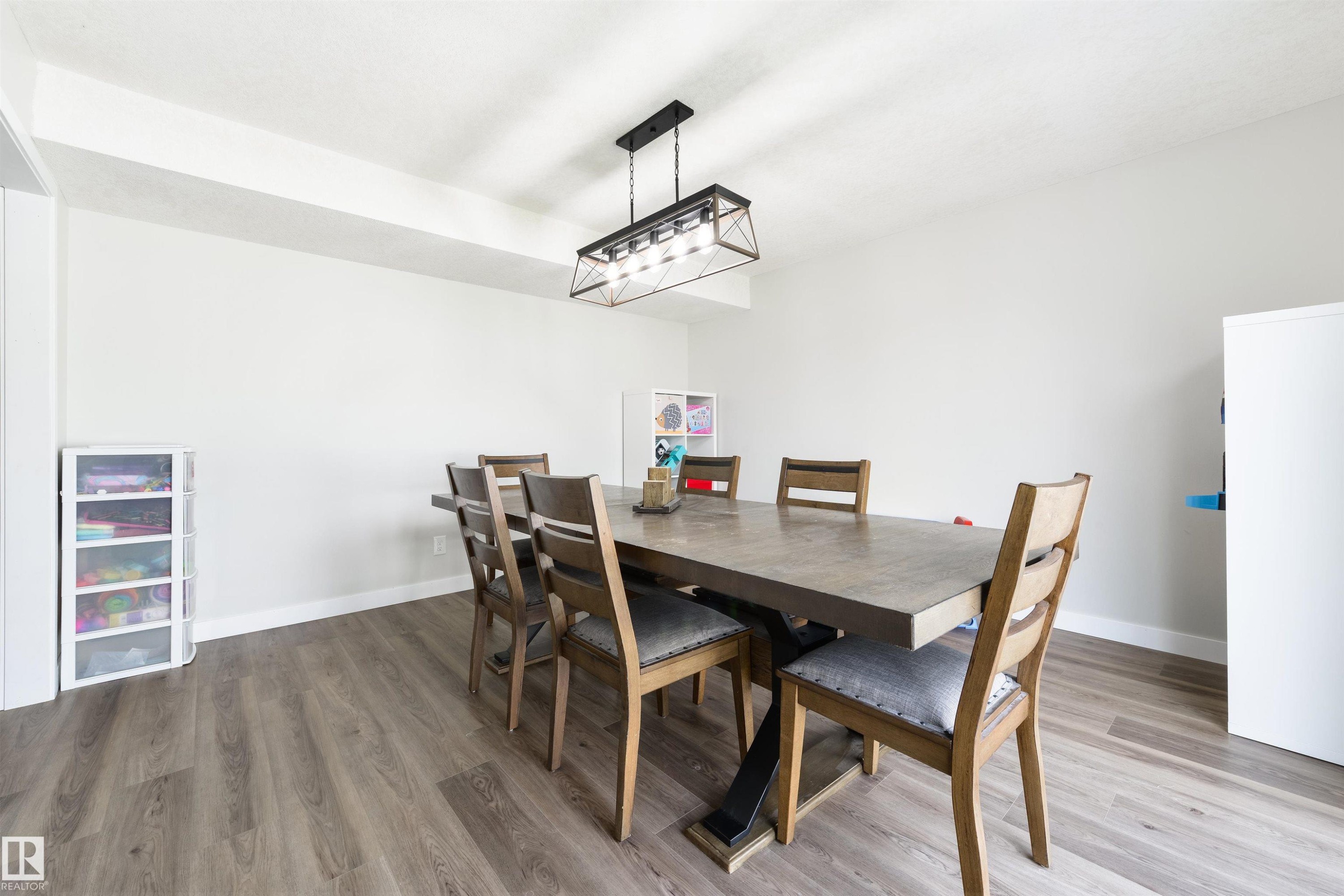 Wood-finish flooring with white baseboards, light-toned walls, and a contemporary ceiling light fixture - 4614 53 Ave, Calmar, AB - Indoor Photo Showing Dining Room