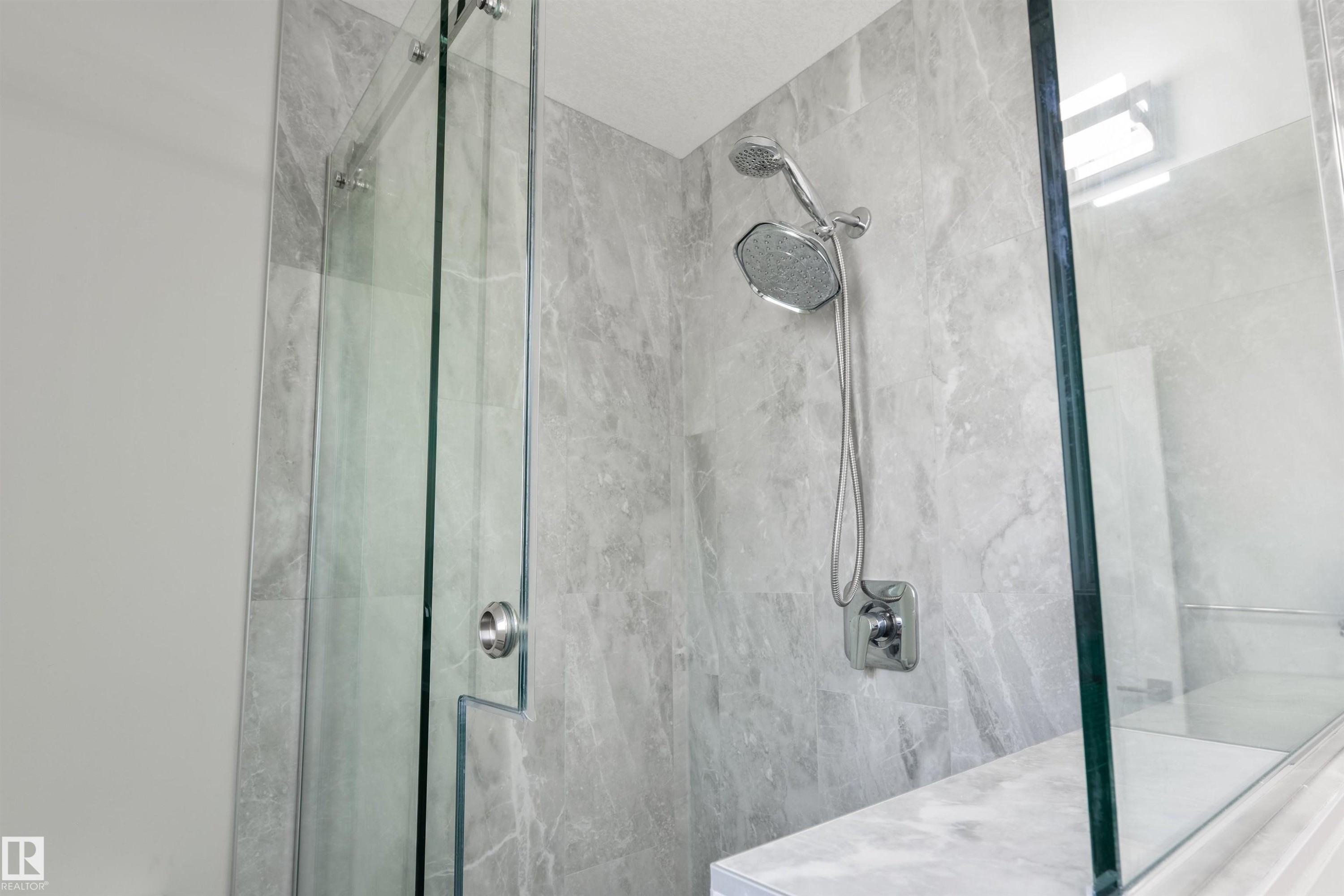 Frameless glass shower enclosure with a built-in bench, tiled walls, and a multi-function showerhead - 4614 53 Ave, Calmar, AB - Indoor Photo Showing Bathroom