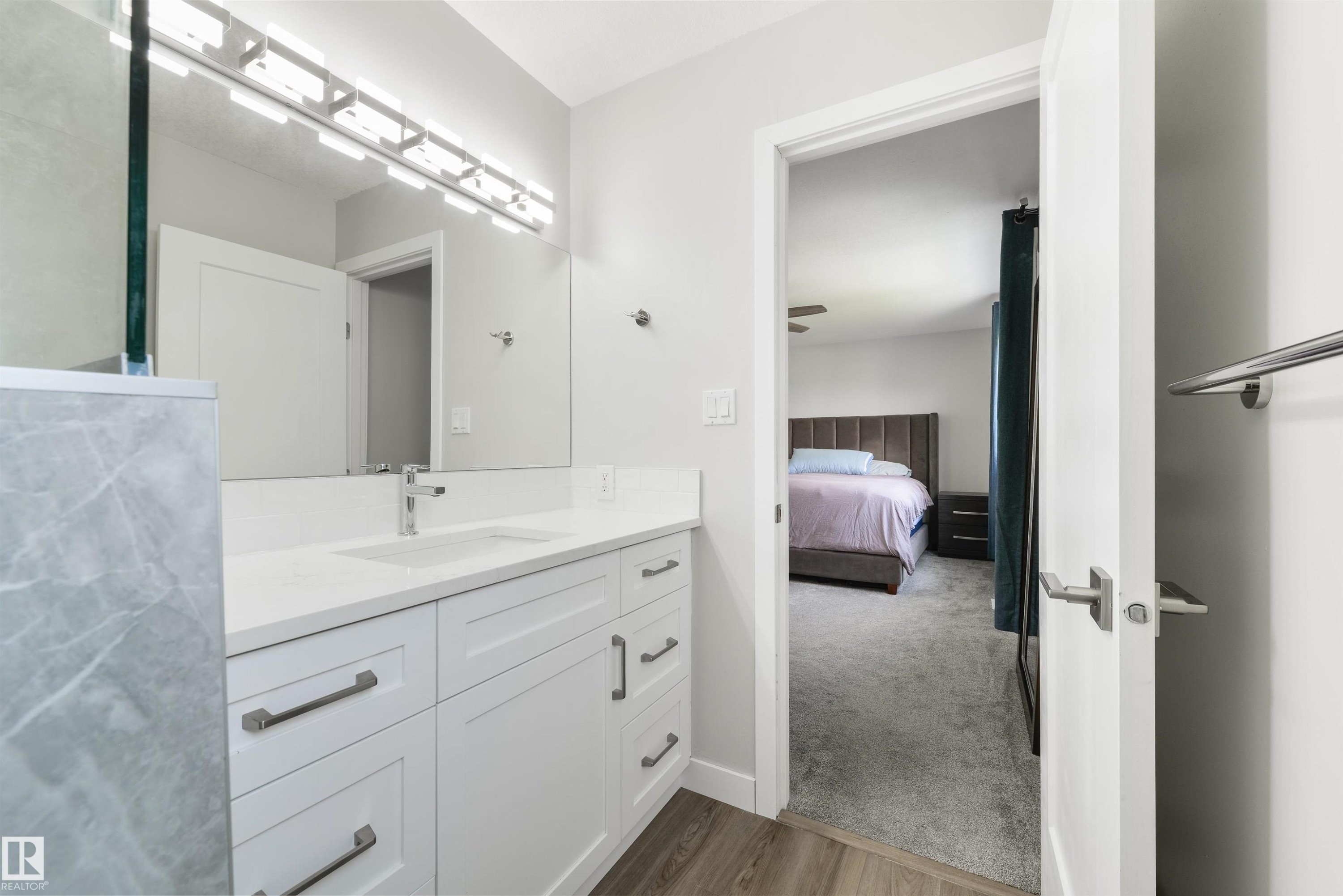 White vanity with integrated sink, chrome faucet, and rectangular mirror - 4614 53 Ave, Calmar, AB - Indoor Photo Showing Bathroom