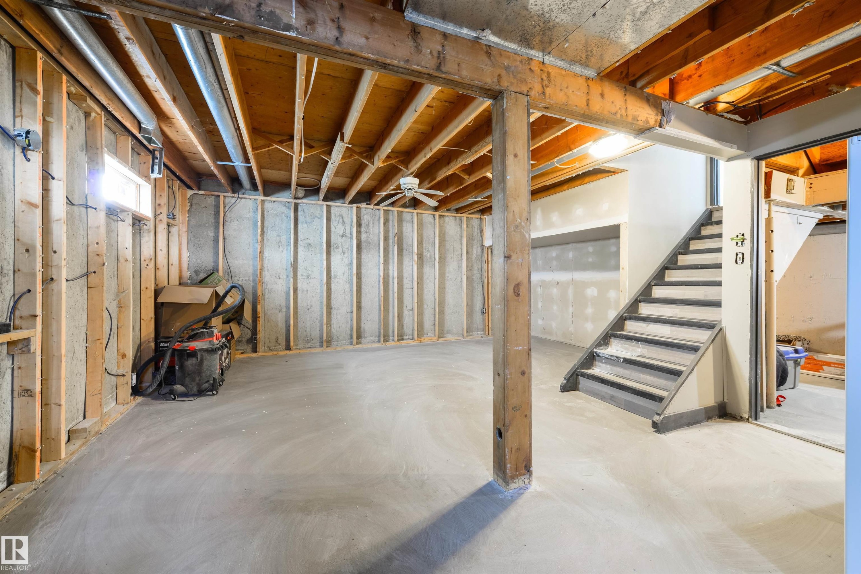 Unfinished basement with exposed wood framing, concrete flooring, and an interior staircase - 4614 53 Ave, Calmar, AB - Indoor Photo Showing Basement