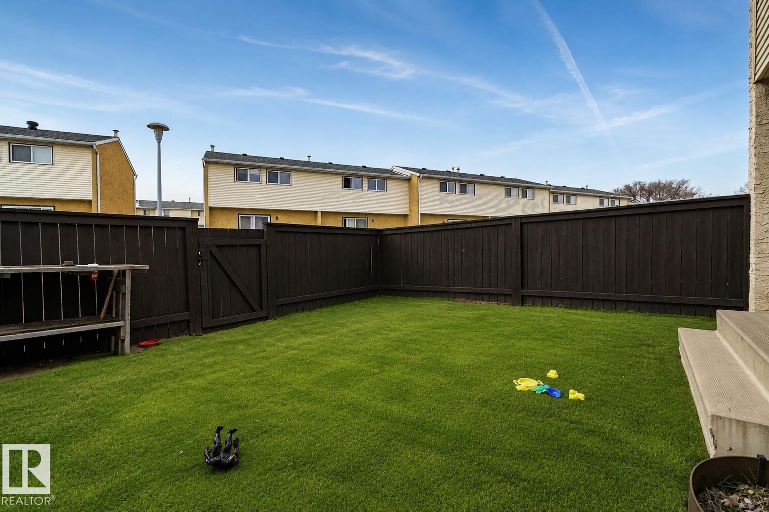 Private fenced yard with a gate, featuring artificial turf and concrete steps - 221 Harrison Dr Nw, Edmonton, AB - Outdoor