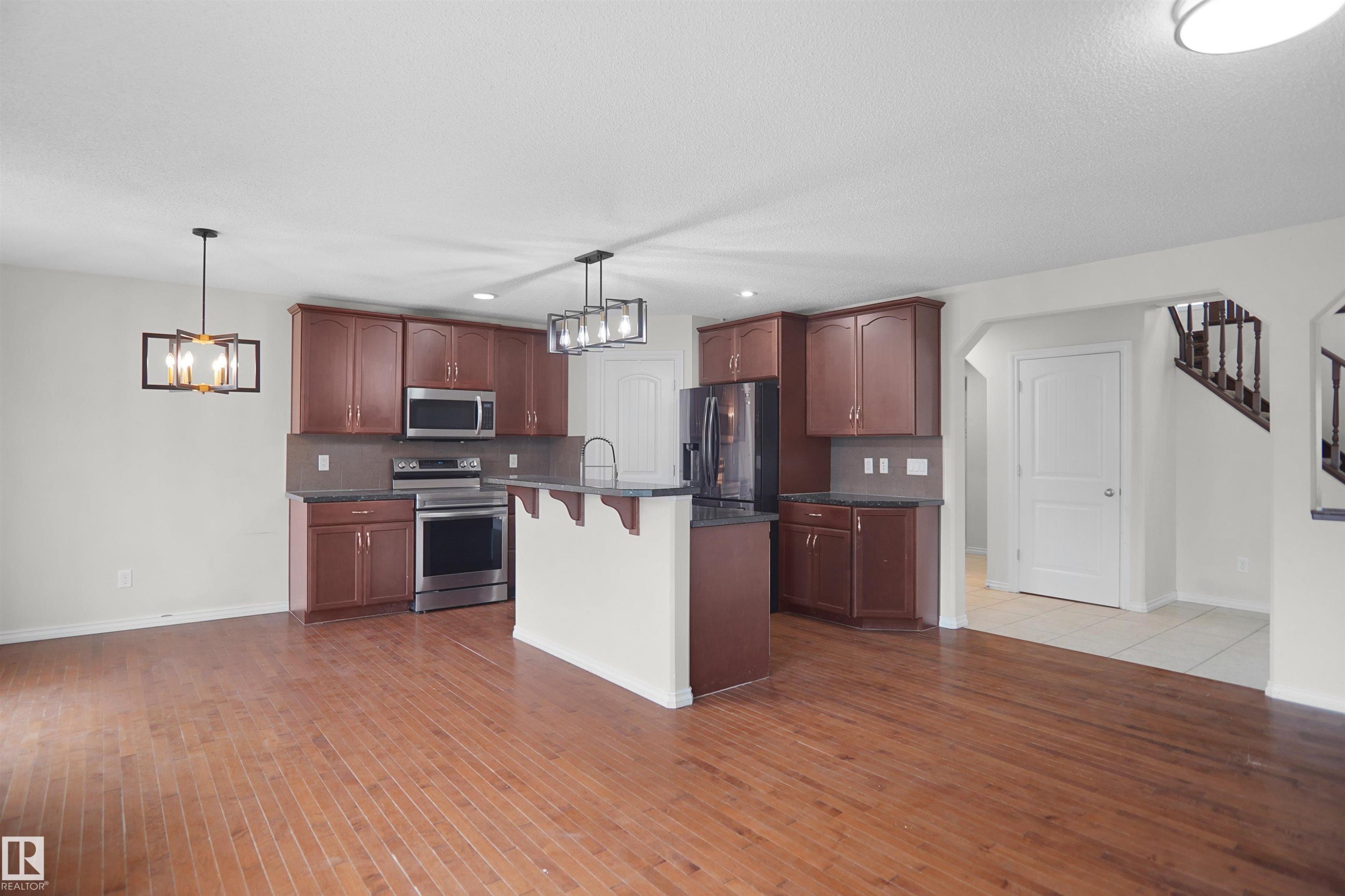 Kitchen featuring wood-finish cabinetry, stainless steel appliances, and dark countertops - 8432 18 Avenue Sw, Edmonton, AB - Indoor Photo Showing Kitchen
