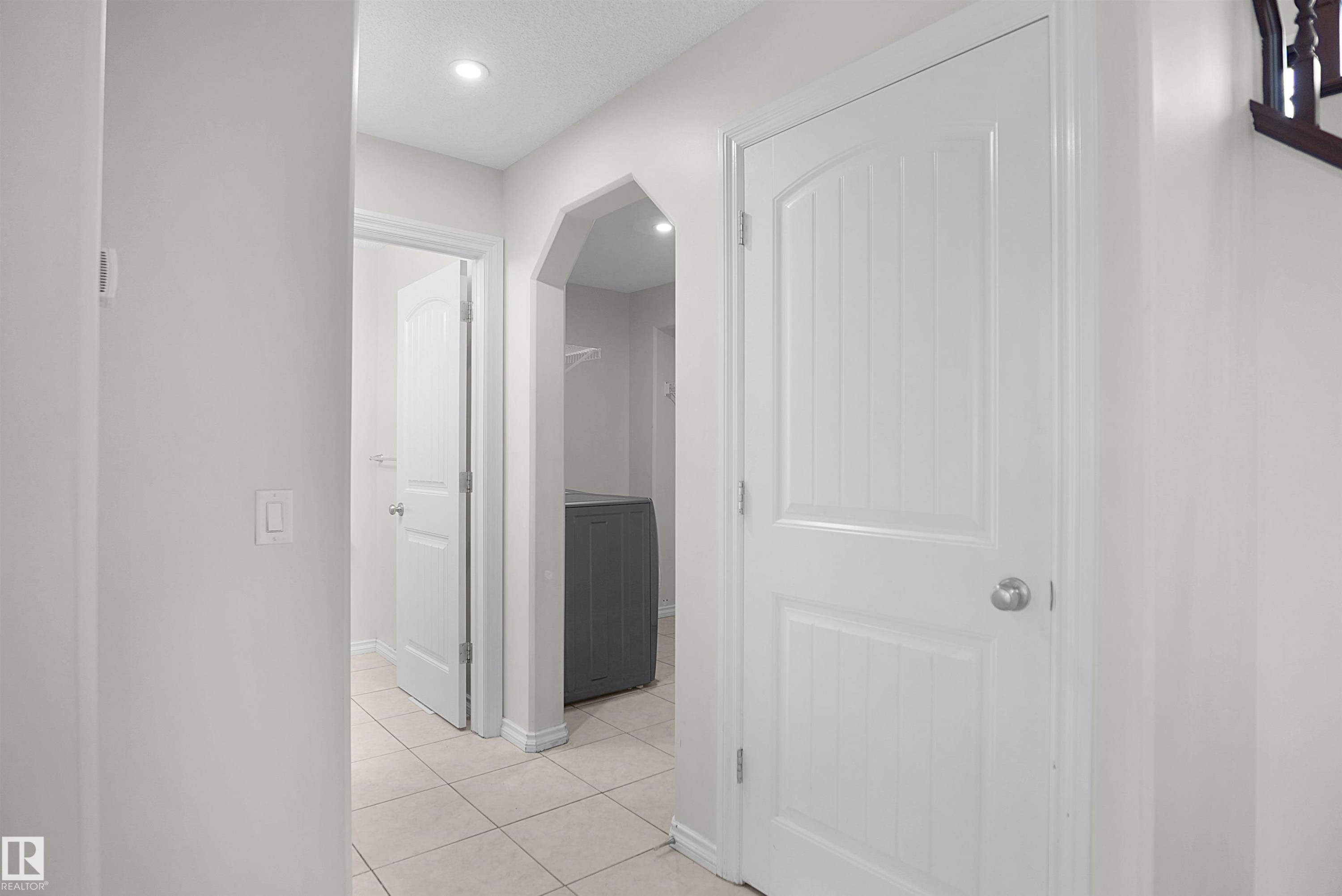 Recessed lighting, tile flooring, arched doorway, paneled interior doors, and a built-in laundry area - 8432 18 Avenue Sw, Edmonton, AB - Indoor Photo Showing Other Room