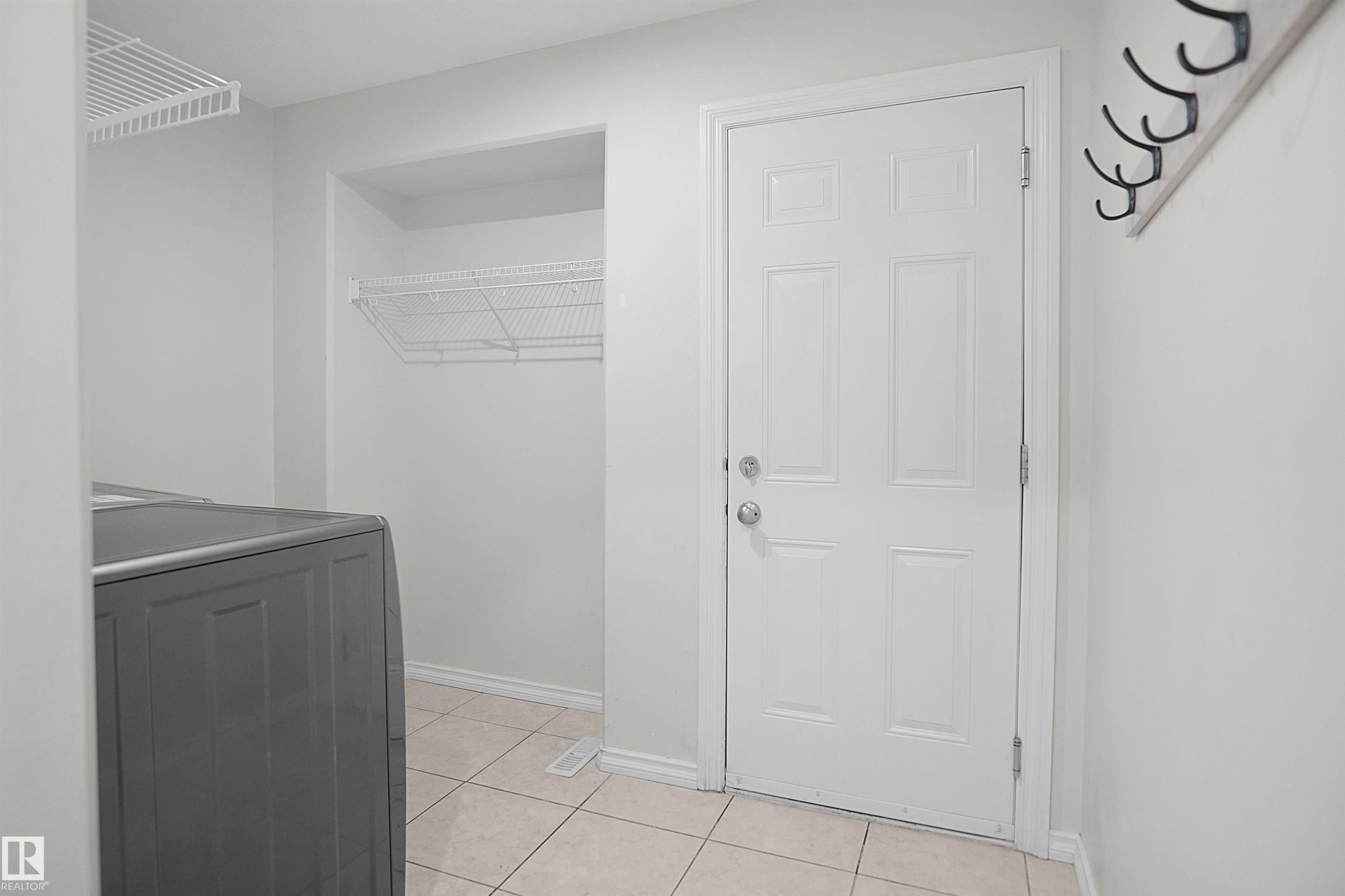 White paneled door with polished chrome hardware, durable tile flooring, and integrated wire shelving - 8432 18 Avenue Sw, Edmonton, AB - Indoor Photo Showing Other Room