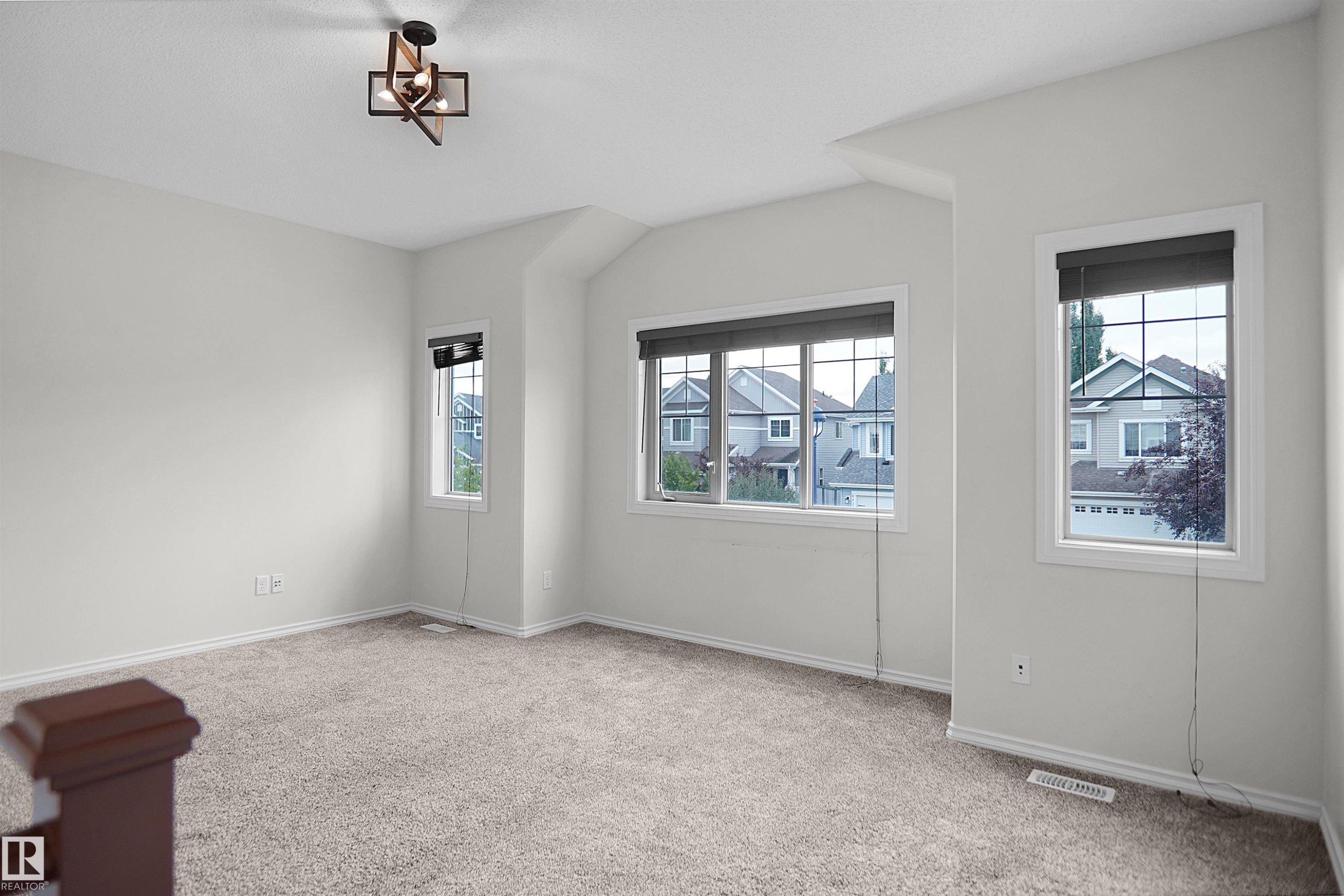 Spacious room featuring carpeting, multiple windows with blinds, a contemporary ceiling light fixture, and freshly painted walls - 8432 18 Avenue Sw, Edmonton, AB - Indoor Photo Showing Other Room