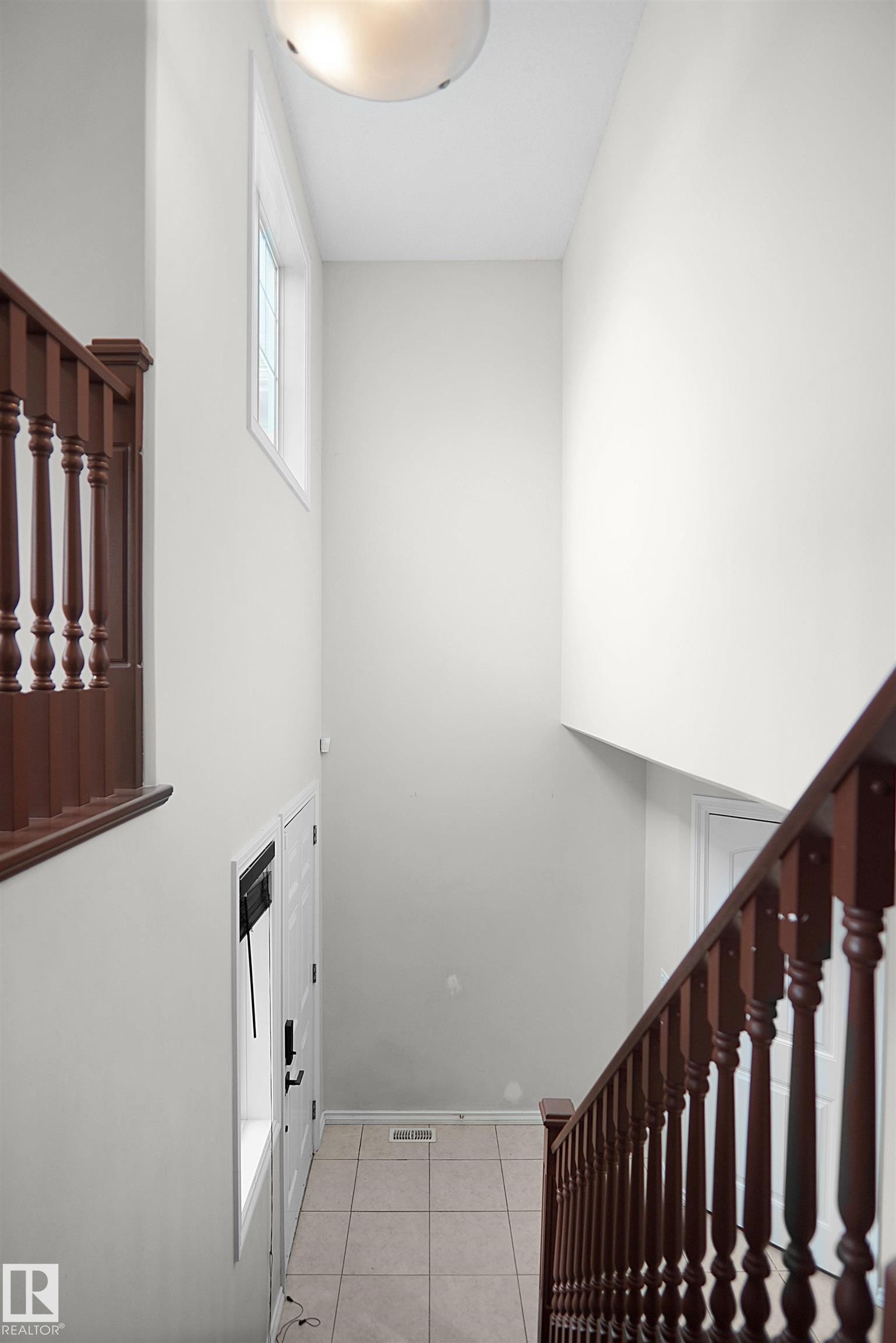 Foyer with tile flooring, wood railings, and a transom window - 8432 18 Avenue Sw, Edmonton, AB - Indoor Photo Showing Other Room