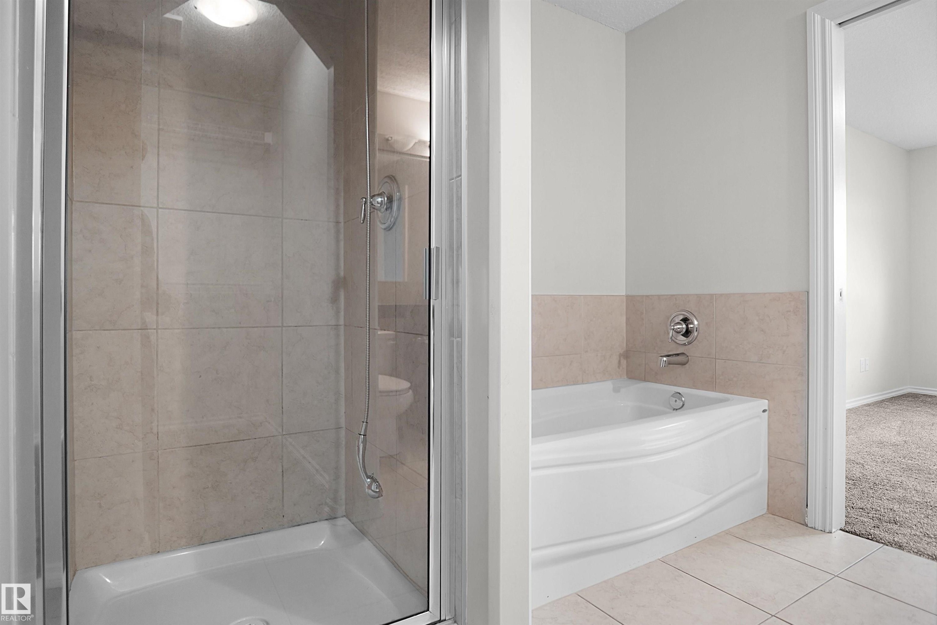 Glass-enclosed shower with tiled walls and a built-in light fixture - 8432 18 Avenue Sw, Edmonton, AB - Indoor Photo Showing Bathroom