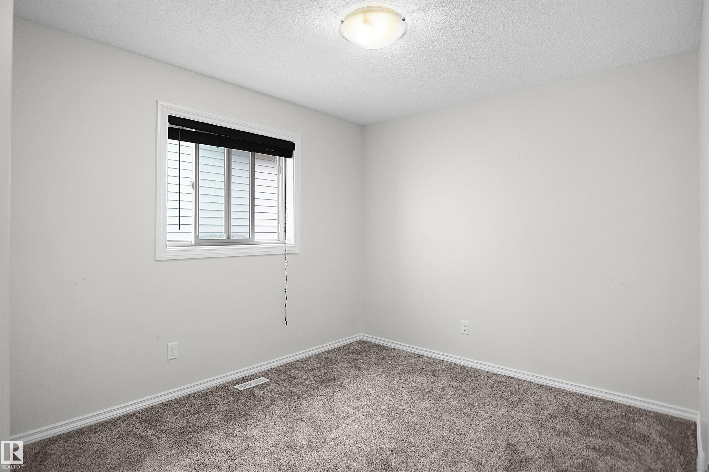 Neutral wall paint, plush carpet flooring, window with blinds, and ceiling-mounted light fixture - 8432 18 Avenue Sw, Edmonton, AB - Indoor Photo Showing Other Room