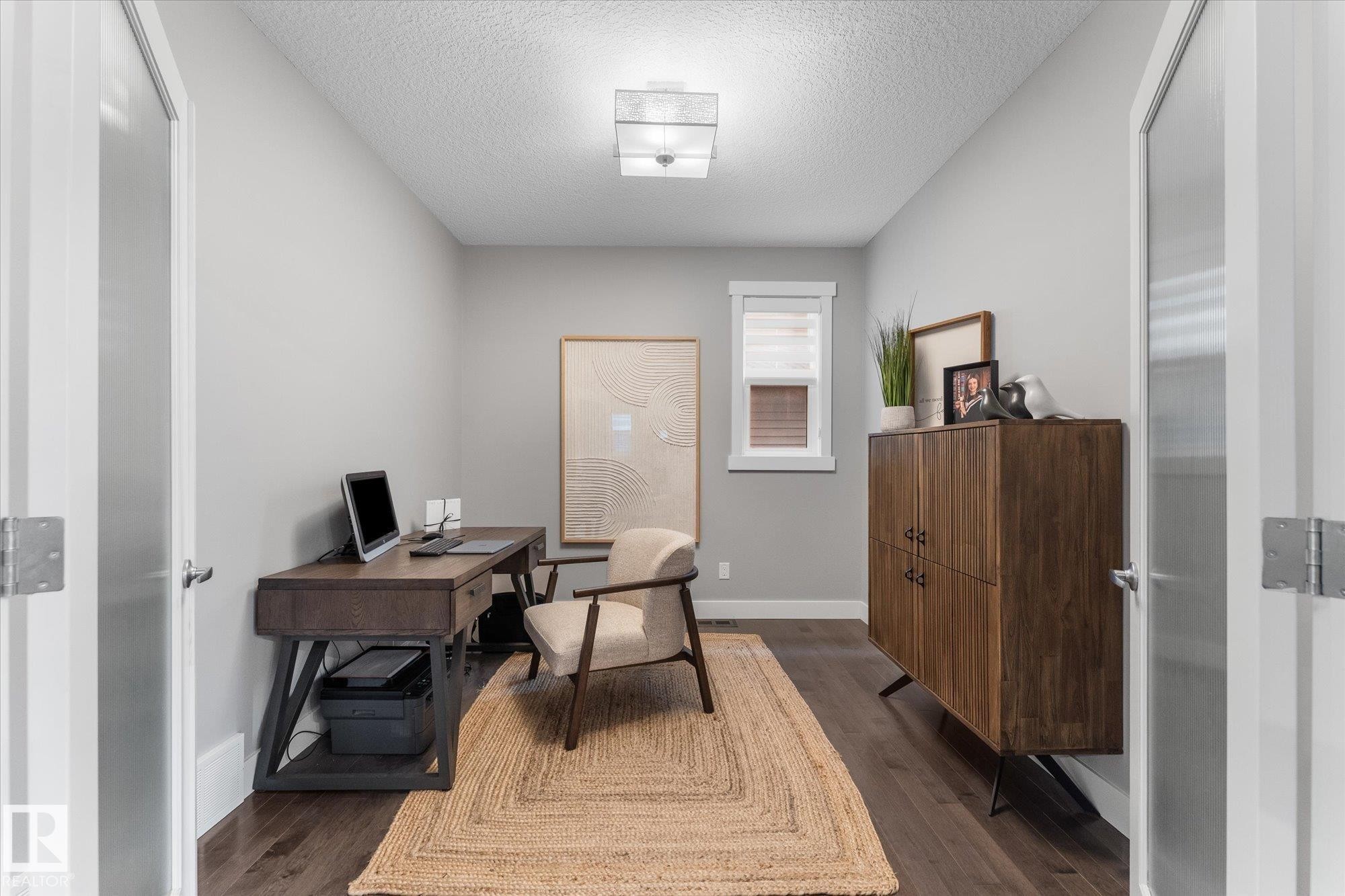 Hardwood-style flooring, neutral wall tones, white trim, recessed lighting, and a window with a roller shade - 5616 Juchli Avenue Nw, Edmonton, AB - Indoor Photo Showing Office