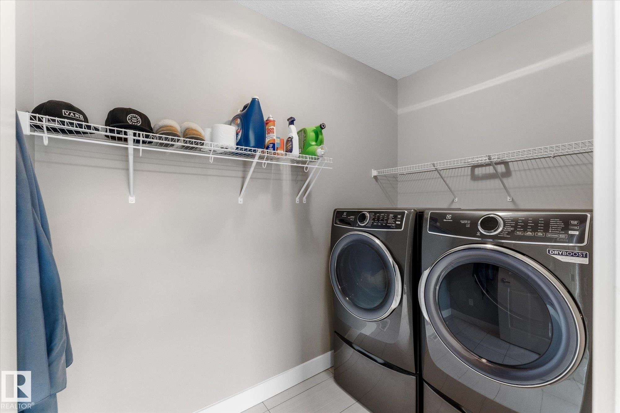 Laundry area featuring a side-by-side washer and dryer, tile flooring, and wire shelving - 5616 Juchli Avenue Nw, Edmonton, AB - Indoor Photo Showing Laundry Room