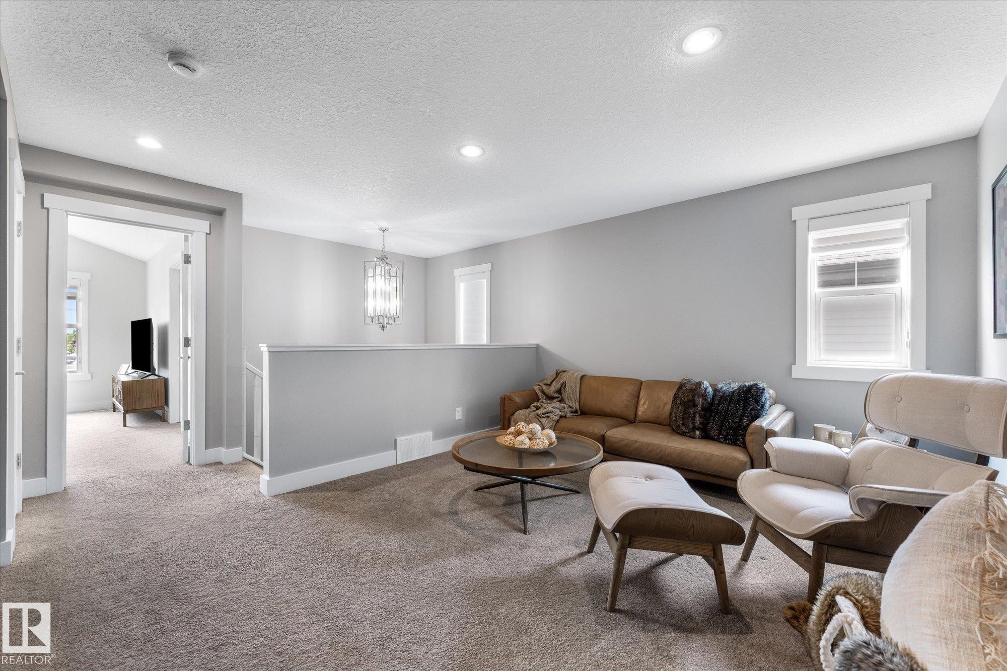 Carpeted landing featuring recessed lighting, a decorative chandelier, and white-trimmed windows - 5616 Juchli Avenue Nw, Edmonton, AB - Indoor Photo Showing Living Room