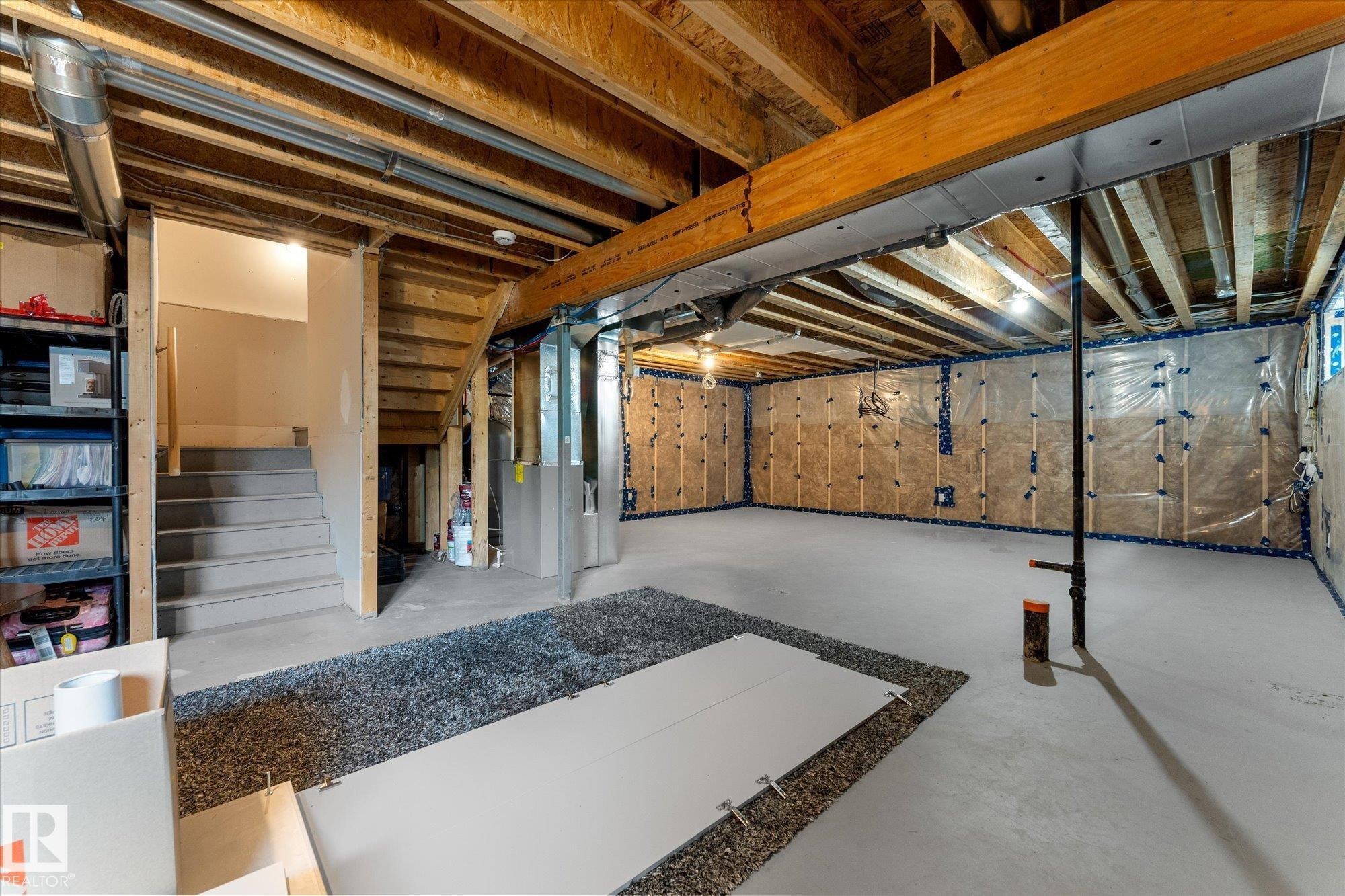 Spacious basement featuring exposed wood beam ceiling, polished concrete flooring with decorative aggregate border, recessed lighting, and built-in cabinetry along the perimeter - 5616 Juchli Avenue Nw, Edmonton, AB - Indoor Photo Showing Basement