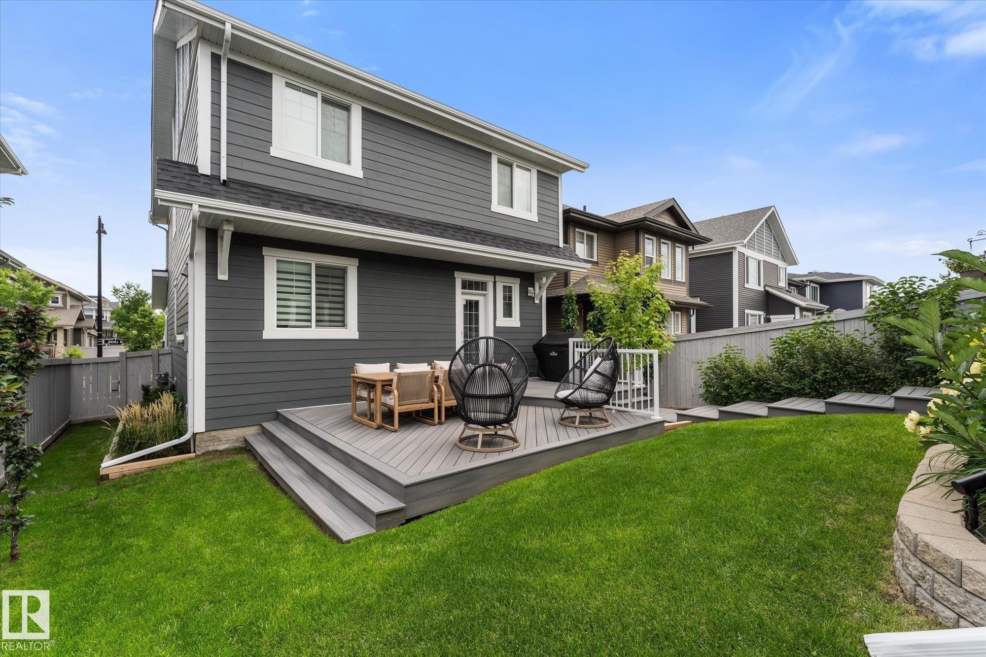 Spacious backyard featuring a multi-level deck, manicured lawn, and a retaining wall with integrated plantings - 5616 Juchli Avenue Nw, Edmonton, AB - Outdoor With Deck Patio Veranda