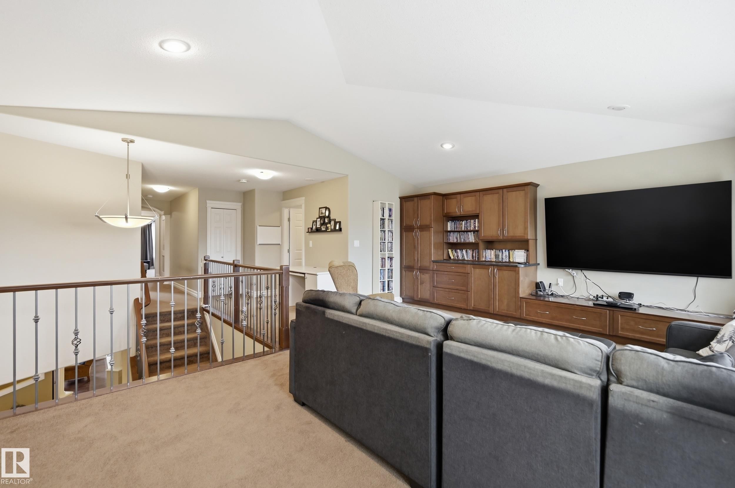 Built-in media cabinetry with wood-finish doors and drawers, recessed ceiling lighting, and a wood-finish staircase with wrought iron balusters - 2416 Warry Place Sw, Edmonton, AB - Indoor Photo Showing Other Room