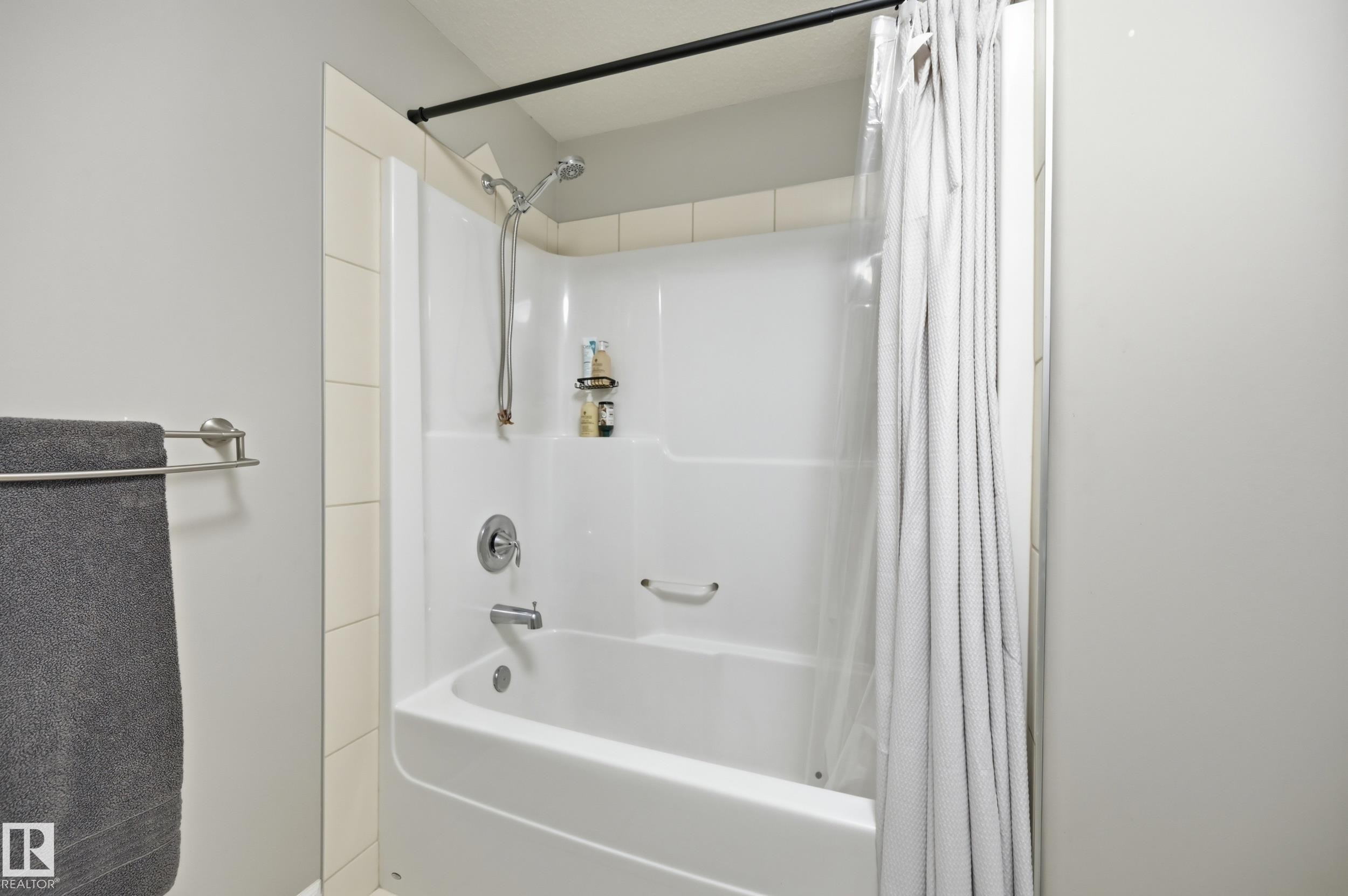 Tub and shower combination with chrome fixtures and integrated shelving - 2416 Warry Place Sw, Edmonton, AB - Indoor Photo Showing Bathroom