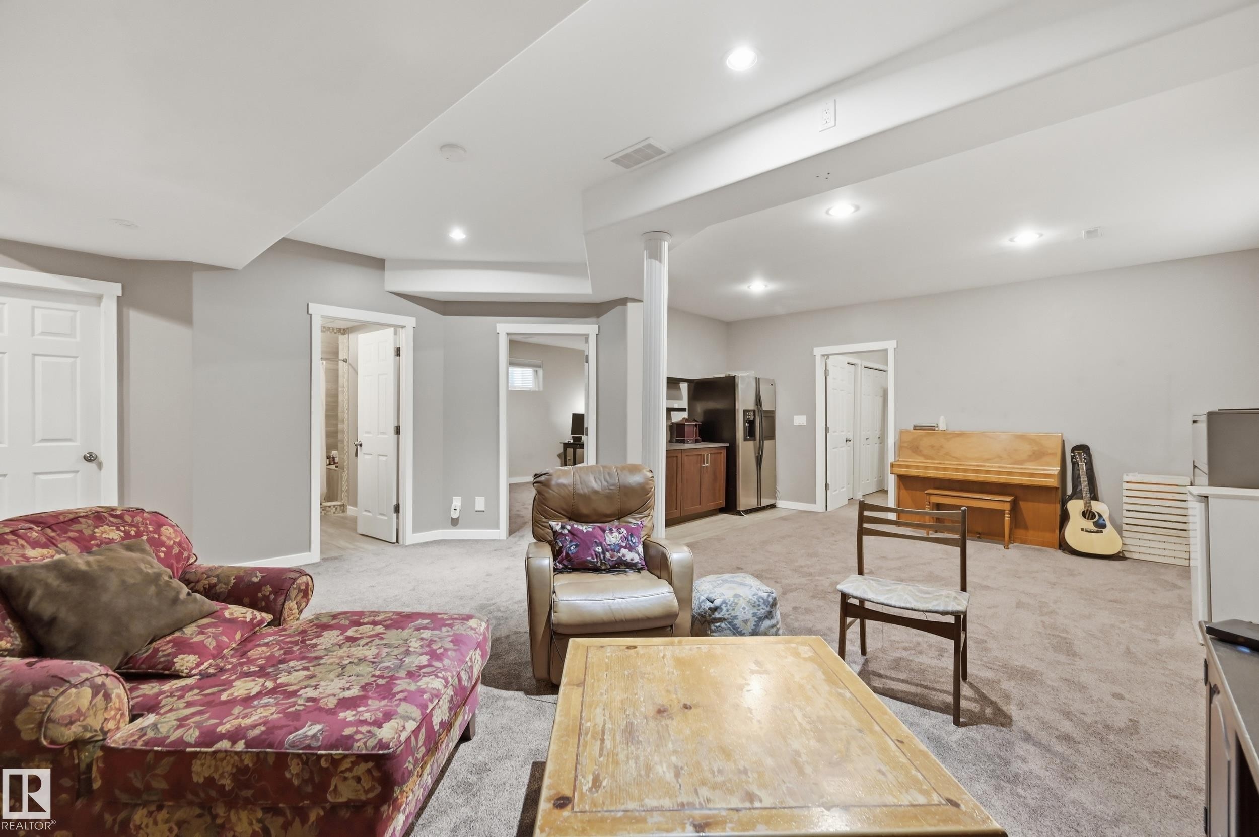 Expansive carpeted area with recessed lighting, multiple doorways, and a built-in wet bar with stainless steel appliances - 2416 Warry Place Sw, Edmonton, AB - Indoor