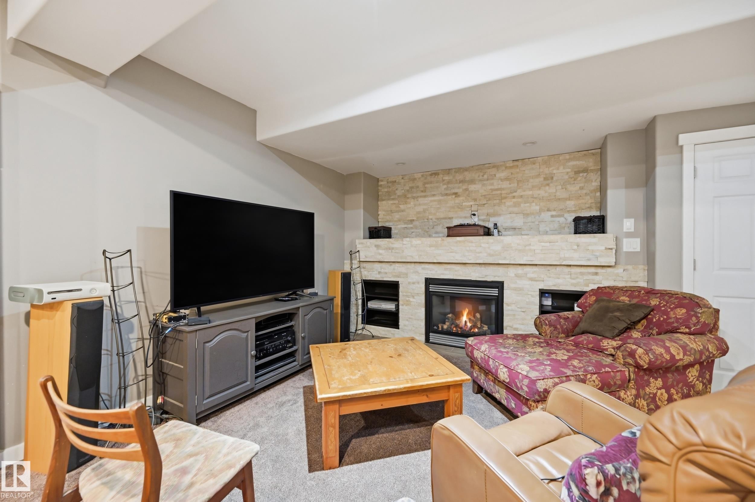 Built-in fireplace with a stone surround, integrated shelving, and carpet flooring - 2416 Warry Place Sw, Edmonton, AB - Indoor Photo Showing Living Room With Fireplace