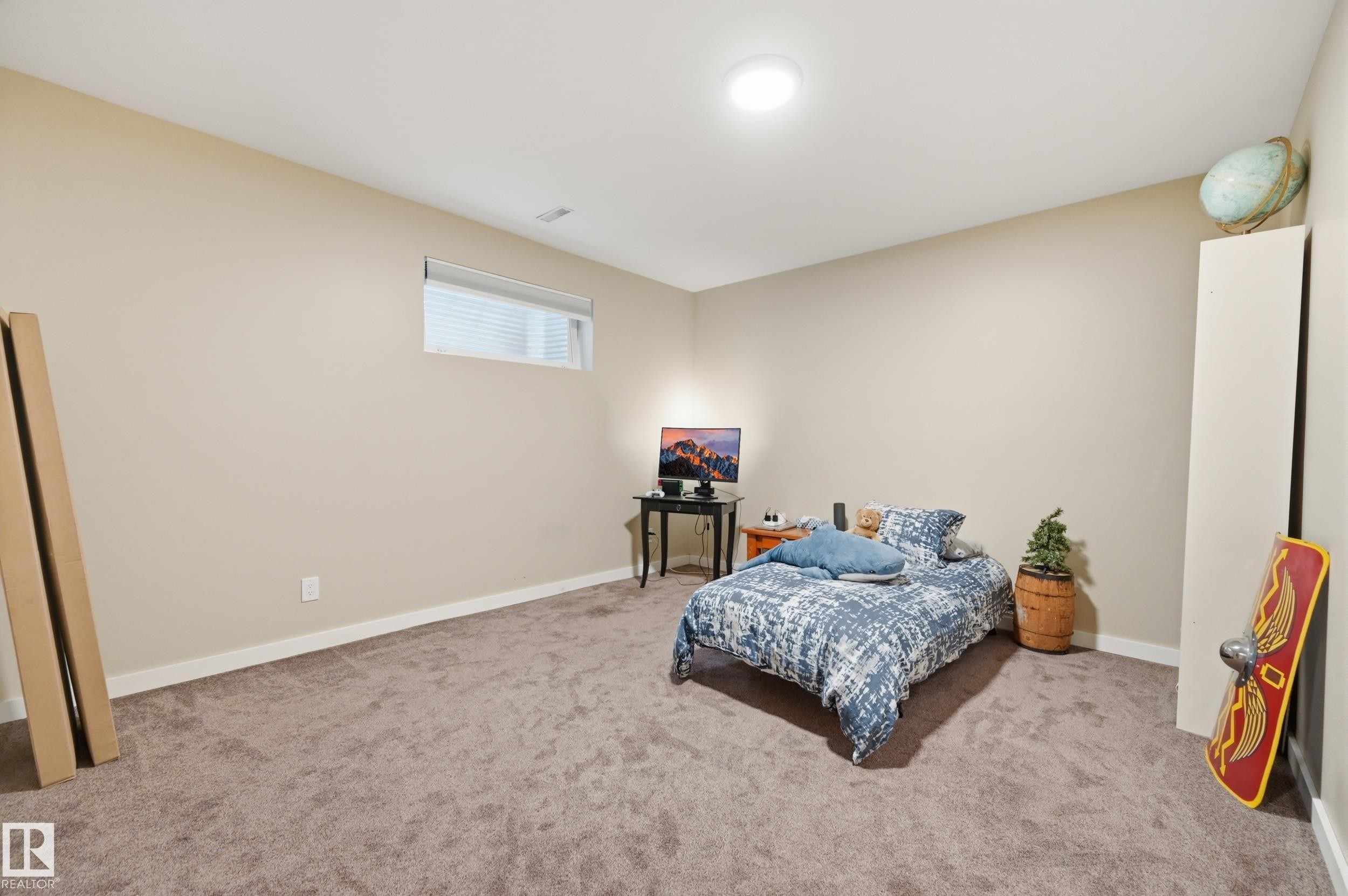 Recessed ceiling lighting illuminates a room featuring a rectangular window, light neutral wall paint, and textured carpeting - 2416 Warry Place Sw, Edmonton, AB - Indoor Photo Showing Bedroom