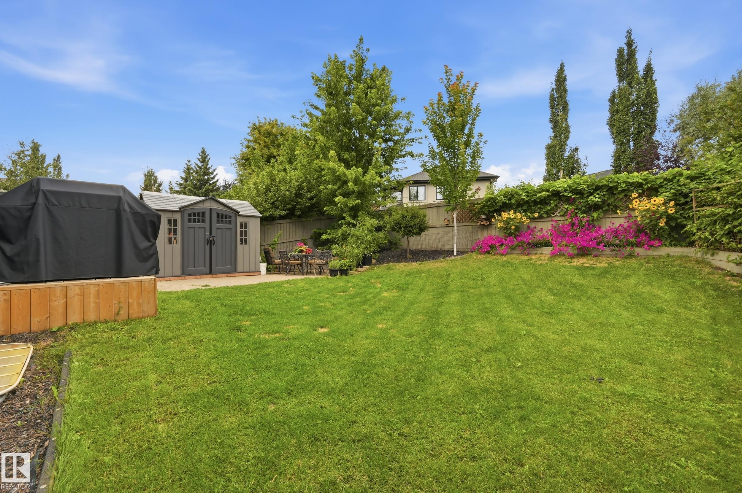 Expansive backyard featuring a manicured lawn, a storage shed, and a paved patio area - 2416 Warry Place Sw, Edmonton, AB - Outdoor