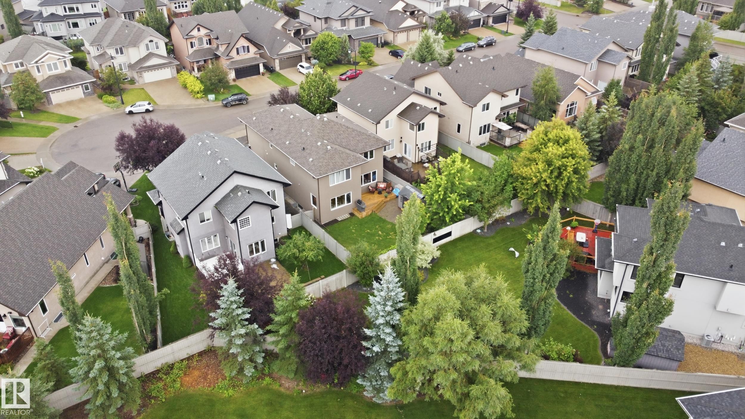 Residential property featuring a grey exterior, a dark grey shingle roof, and a private backyard with mature landscaping - 2416 Warry Place Sw, Edmonton, AB - Outdoor With View