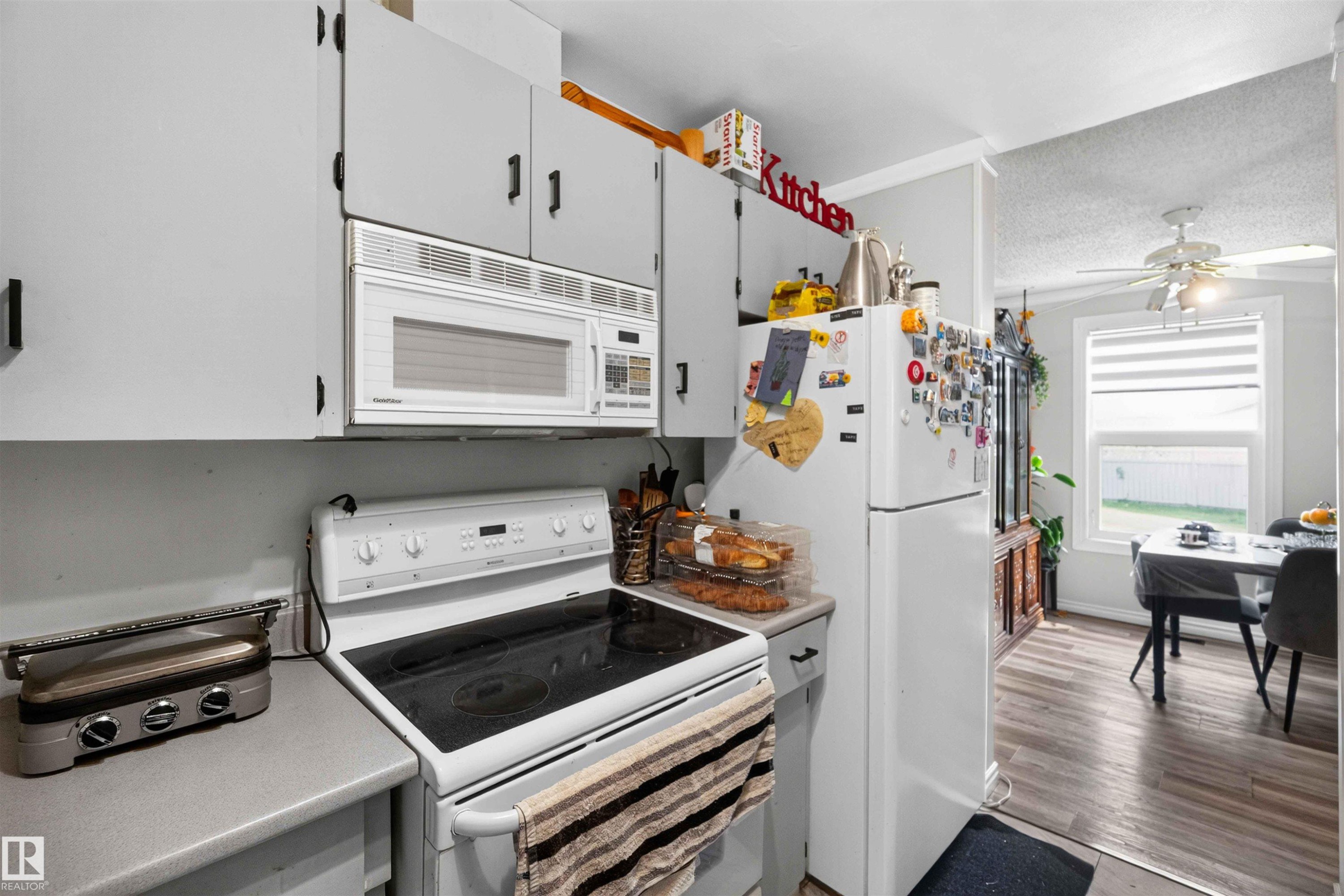 Kitchen featuring white appliances, gray cabinetry with dark hardware, and wood-finish flooring - 17127 109 Street Nw, Edmonton, AB - Indoor Photo Showing Kitchen