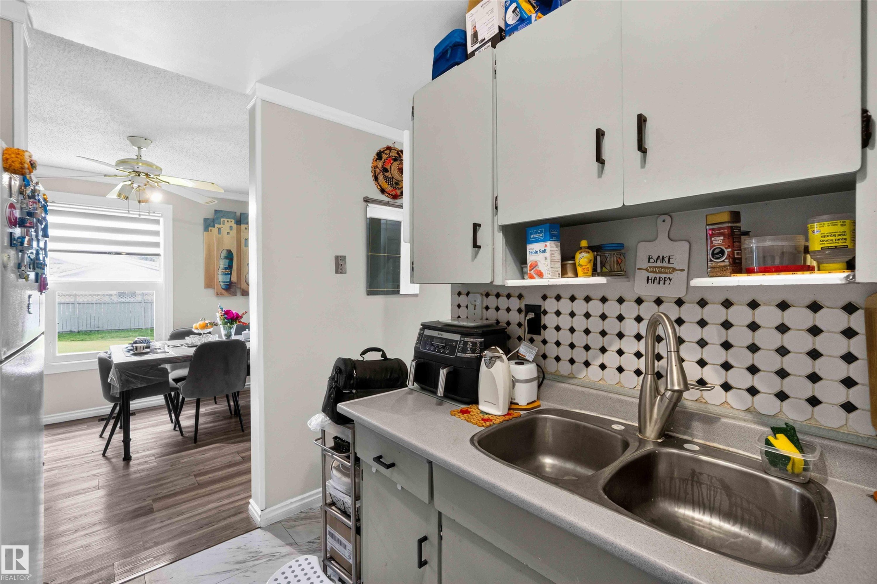 Dual basin stainless steel sink with a high-arc faucet, complemented by a tiled backsplash - 17127 109 Street Nw, Edmonton, AB - Indoor Photo Showing Kitchen With Double Sink